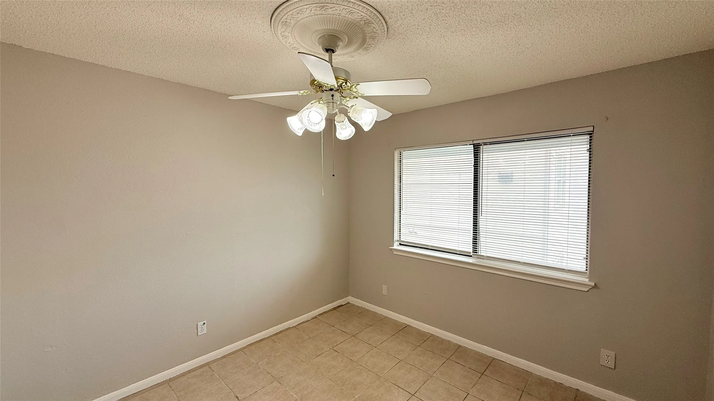 Room featuring a window with horizontal blinds, a ceiling fan with integrated lighting, and neutral wall paint