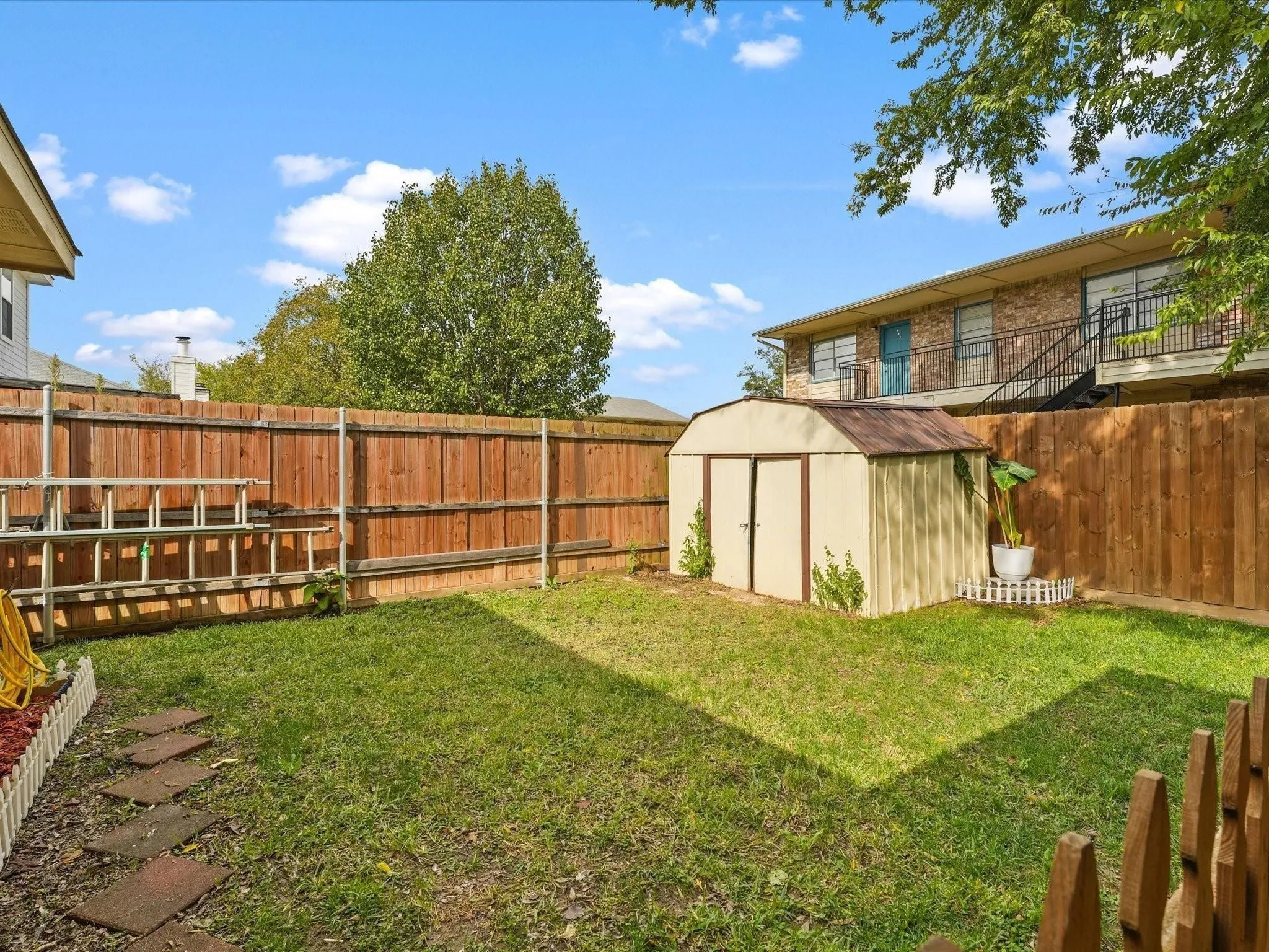 Fenced backyard featuring a storage shed and a stone walkway