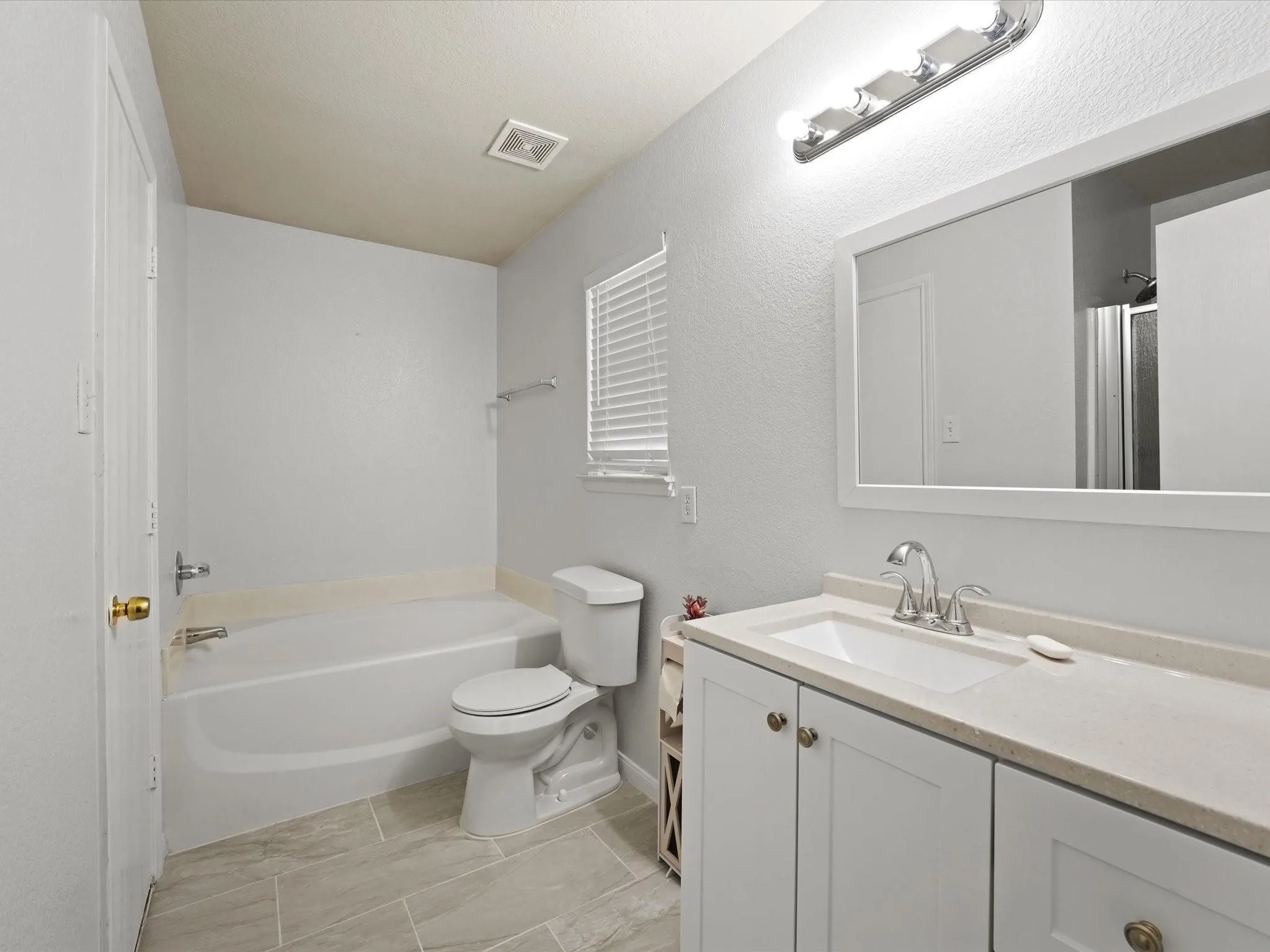 Bathroom featuring a white vanity with an integrated sink, polished chrome faucet, and a framed mirror