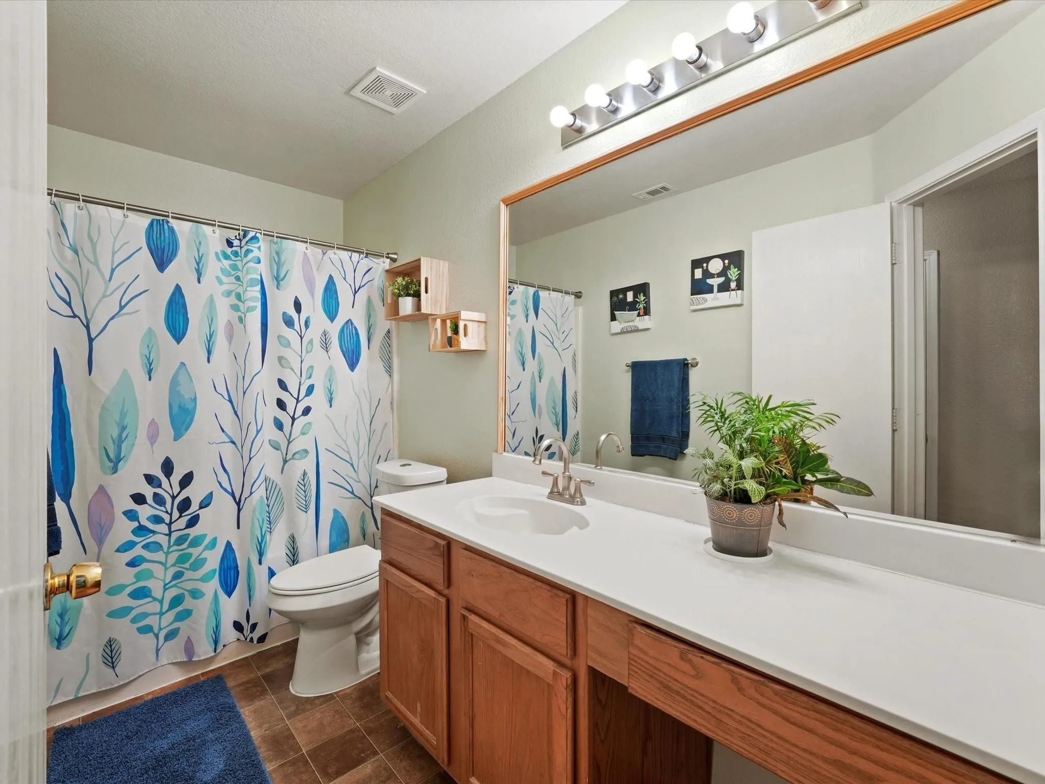 Vanity with integrated sink, wood-finish cabinetry, and expansive mirror
