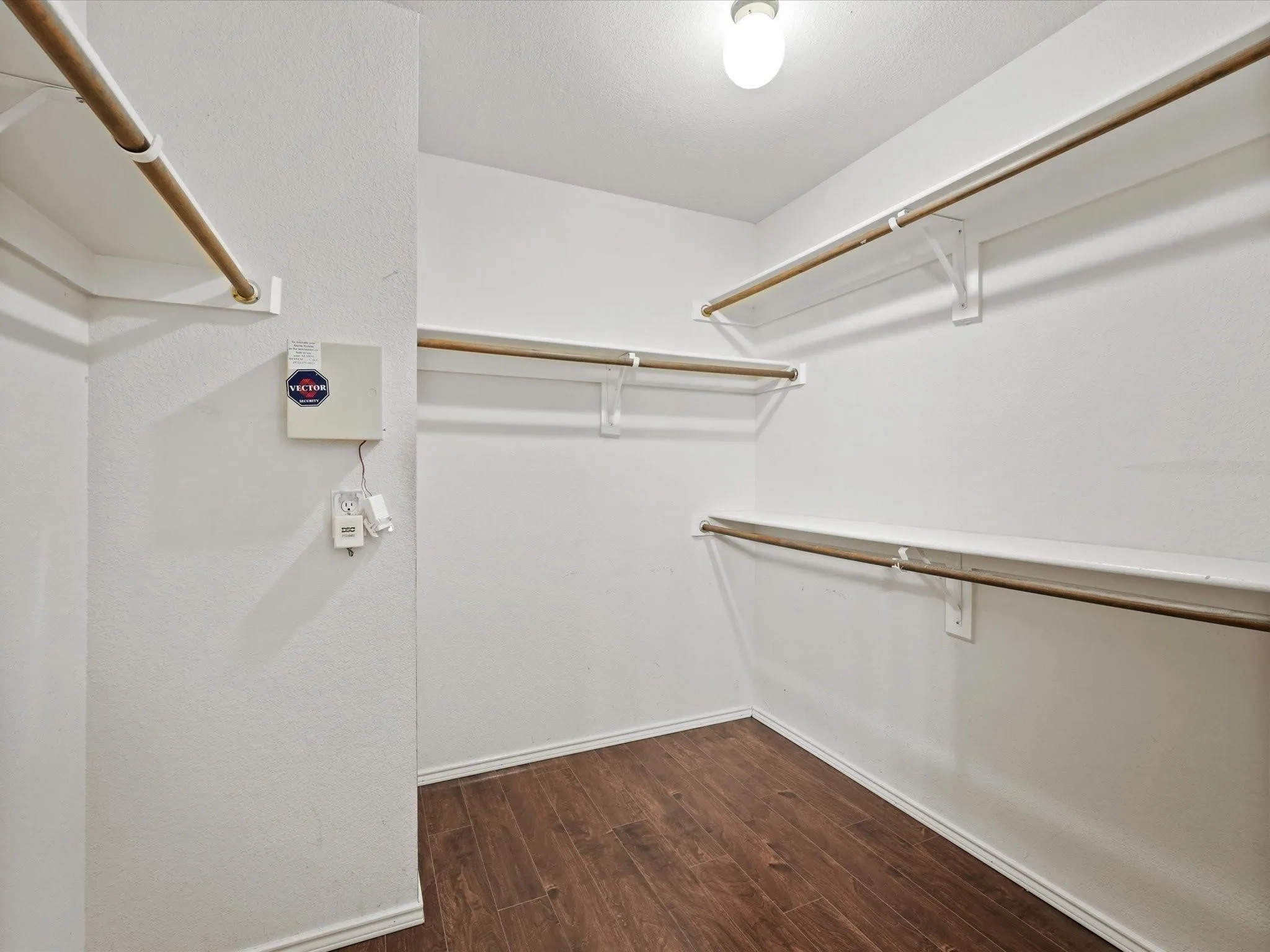 Walk-in closet featuring wood-finish flooring, multiple shelving units, and clothing rods