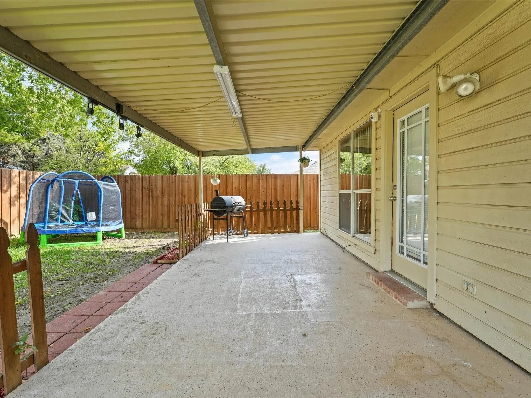 Covered patio with concrete flooring, siding exterior, and a privacy fence