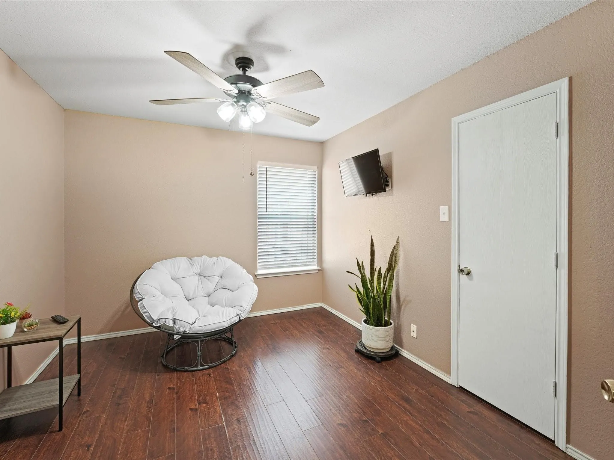 Wood-finish flooring, ceiling fan with integrated lighting, window with horizontal blinds, and white interior door