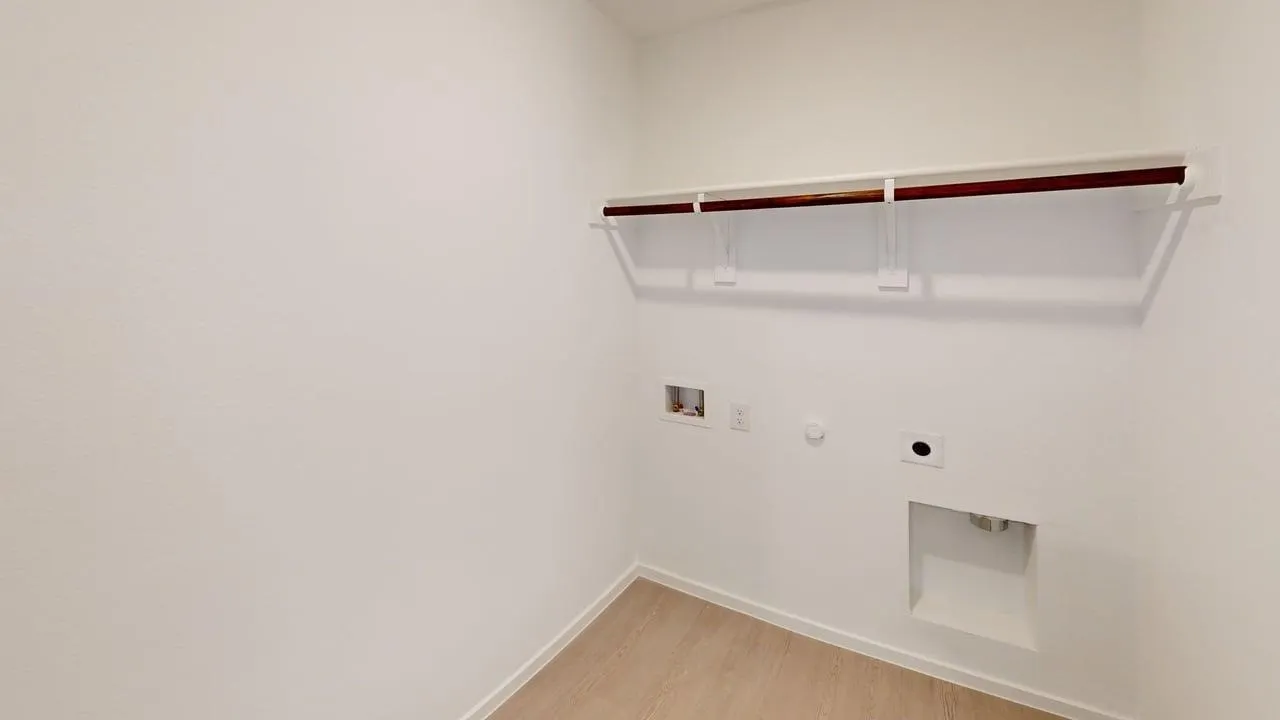Utility room featuring wood-finish flooring, white walls, built-in shelving, and a clothing rod