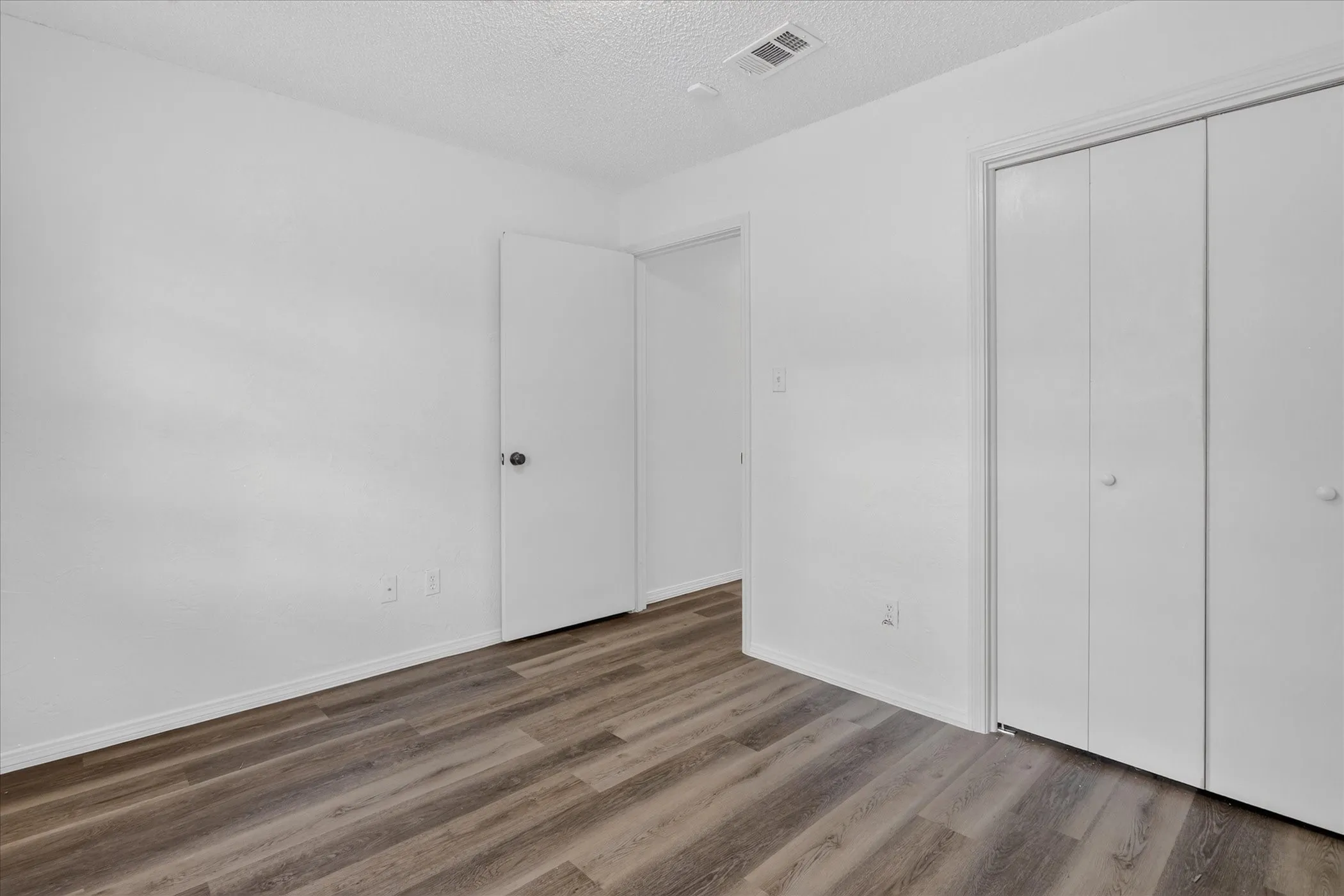 Wood-finish flooring, white painted walls, and bi-fold closet doors