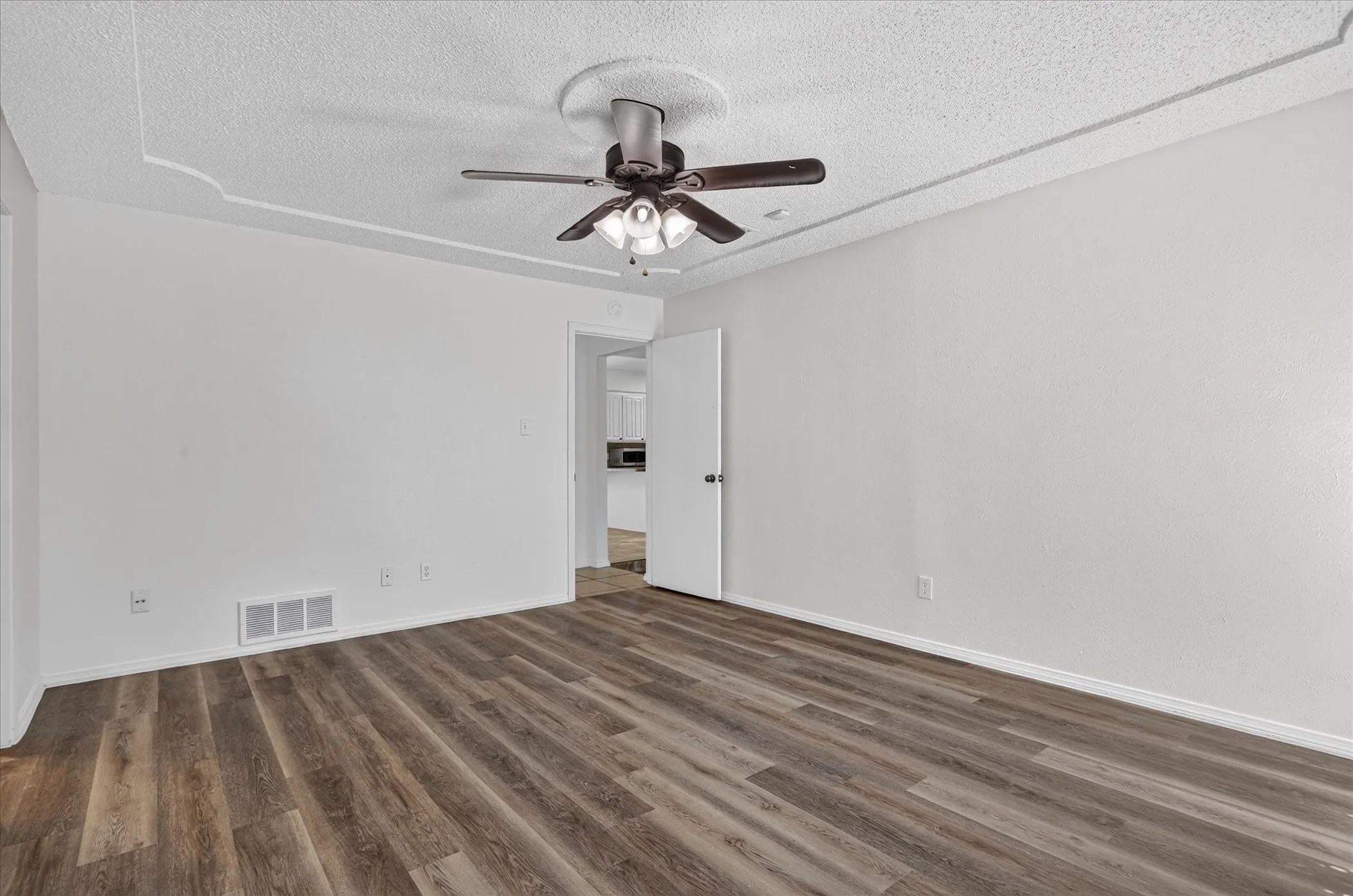 Wood-finish flooring, ceiling fan with integrated lighting, and white walls