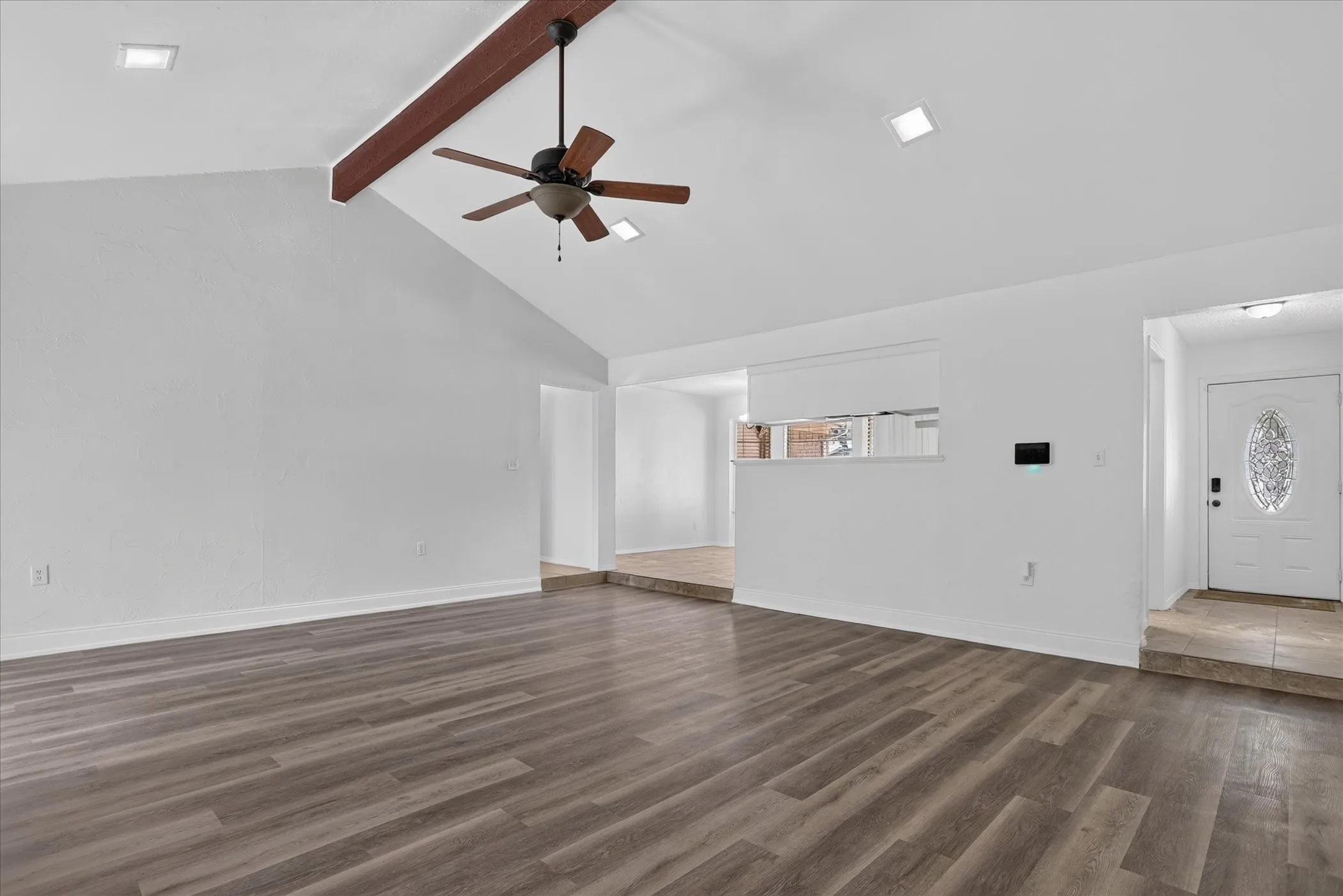 Vaulted ceiling with exposed wood beam, recessed lighting, wood-finish flooring, and ceiling fan