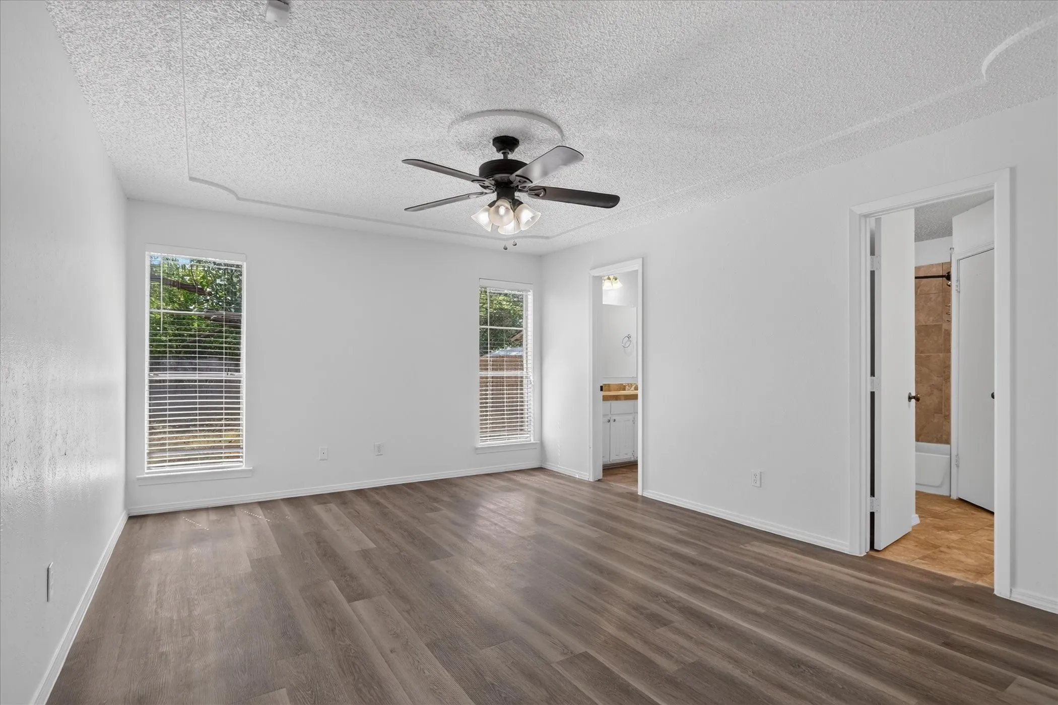Wood-finish flooring, white walls, and a ceiling fan with light fixture