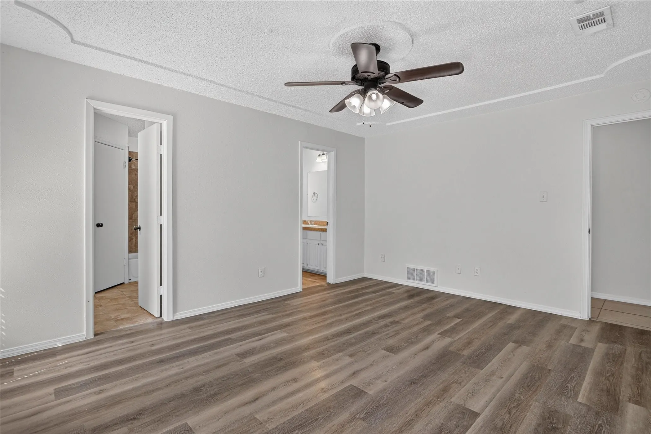 Wood-finish flooring, ceiling fan with light fixture, and crown molding details
