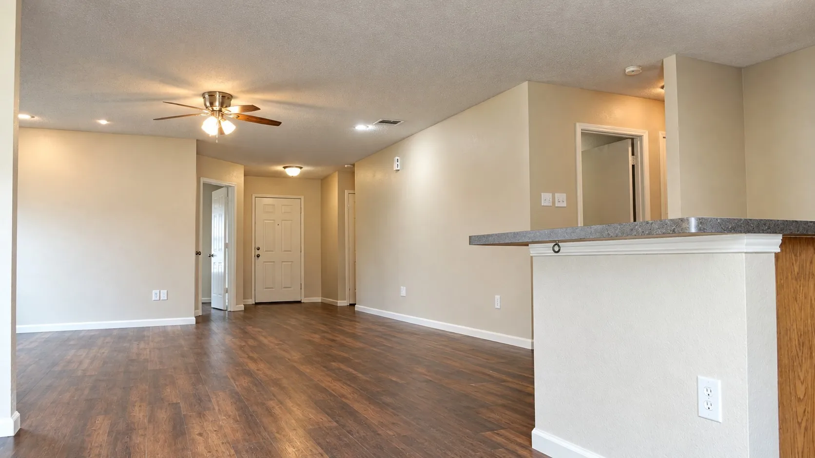Wood-finish flooring, ceiling fan with light fixture, recessed lighting, raised breakfast bar, and neutral wall tones