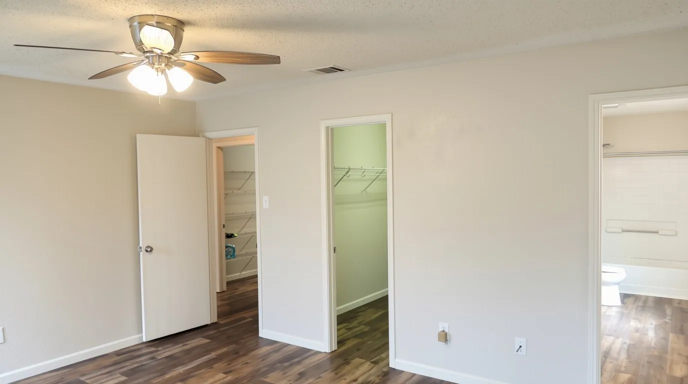 Wood-finish flooring, ceiling fan with integrated lighting, neutral wall paint, white trim, and wire closet shelving