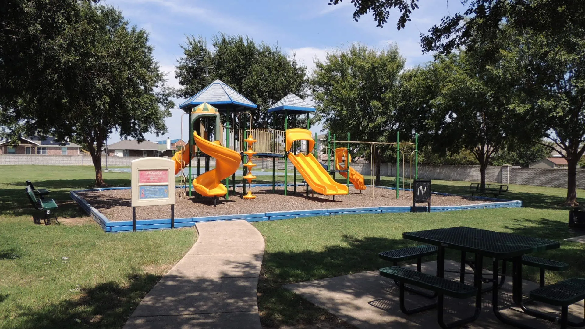 Community playground featuring a multi-level play structure, swings, and slides