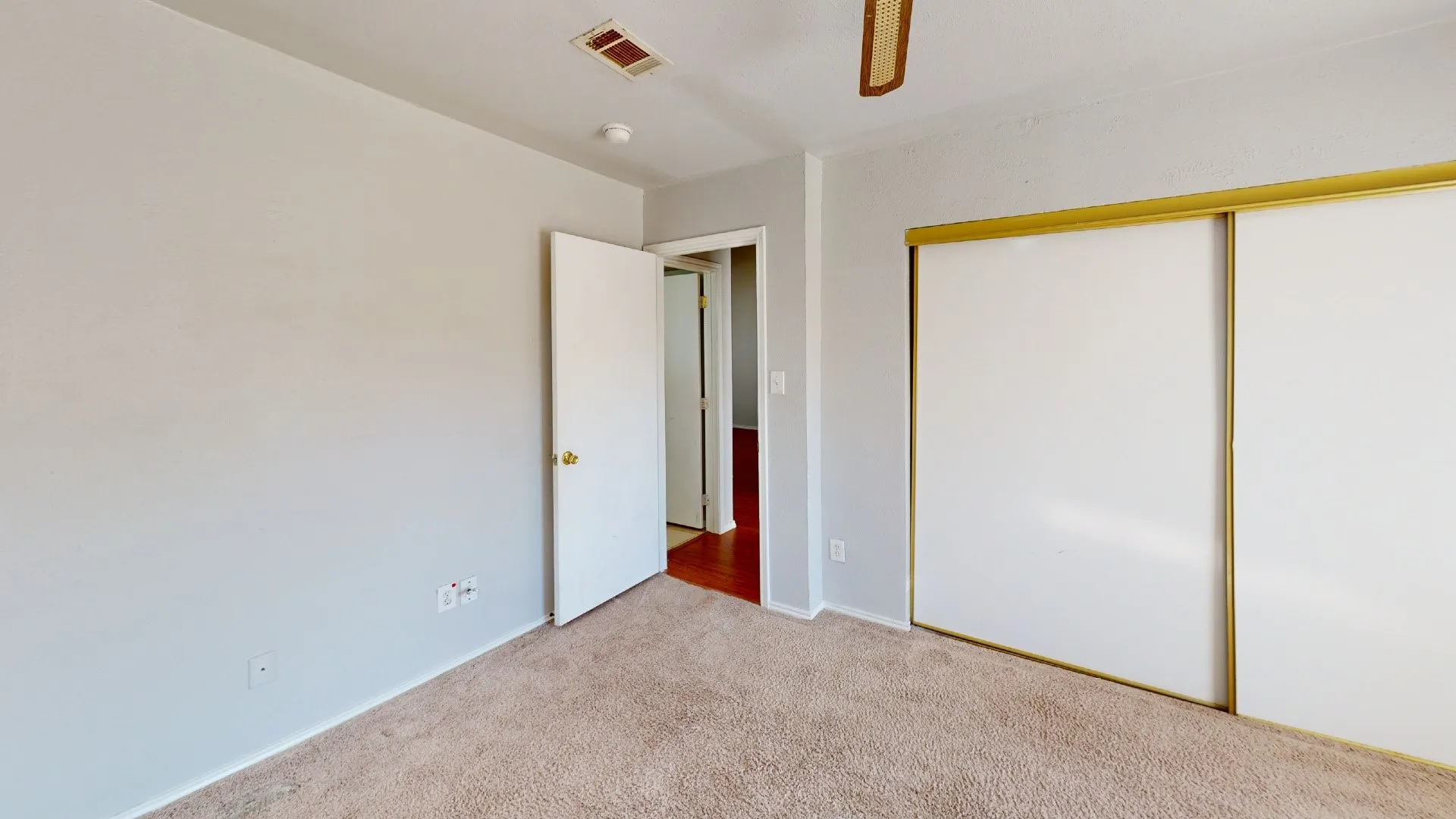 Wall-to-wall carpeting with light-toned walls and a ceiling fan