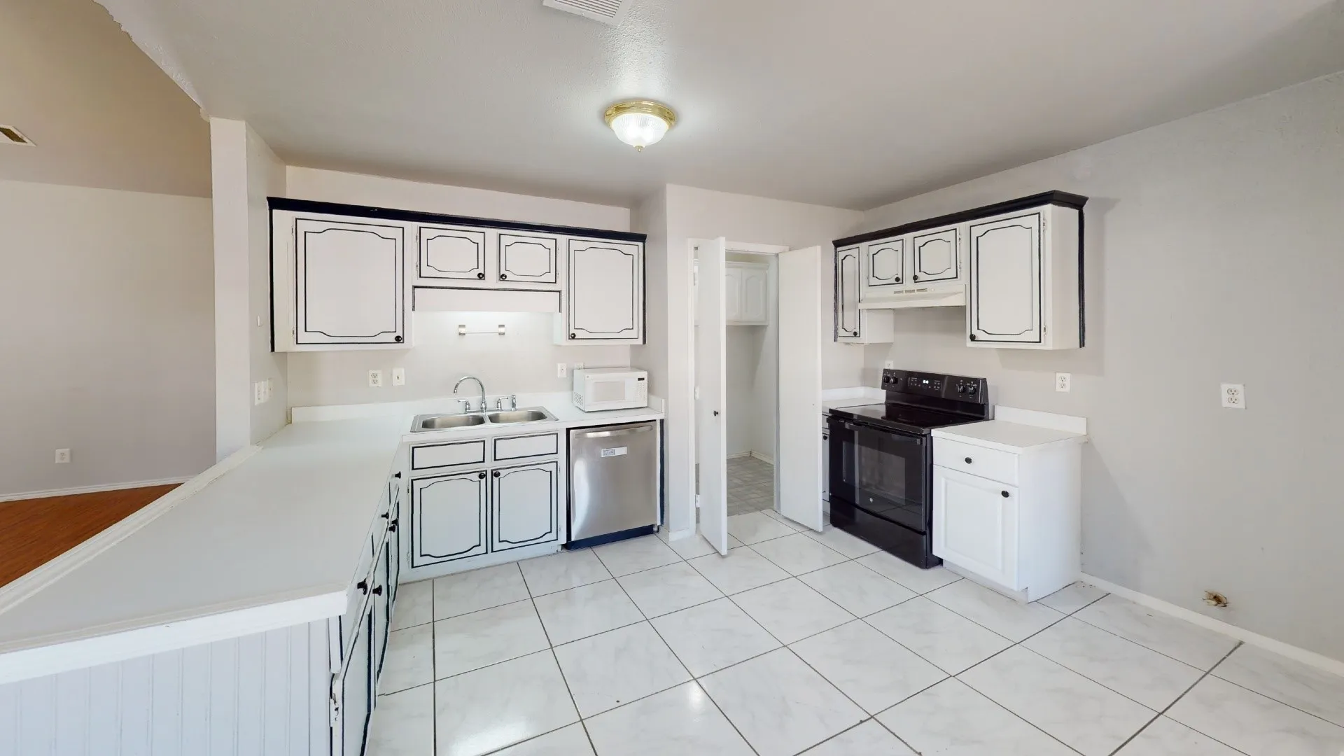 Kitchen featuring white cabinetry with dark trim, white countertops, tile flooring, and integrated black range