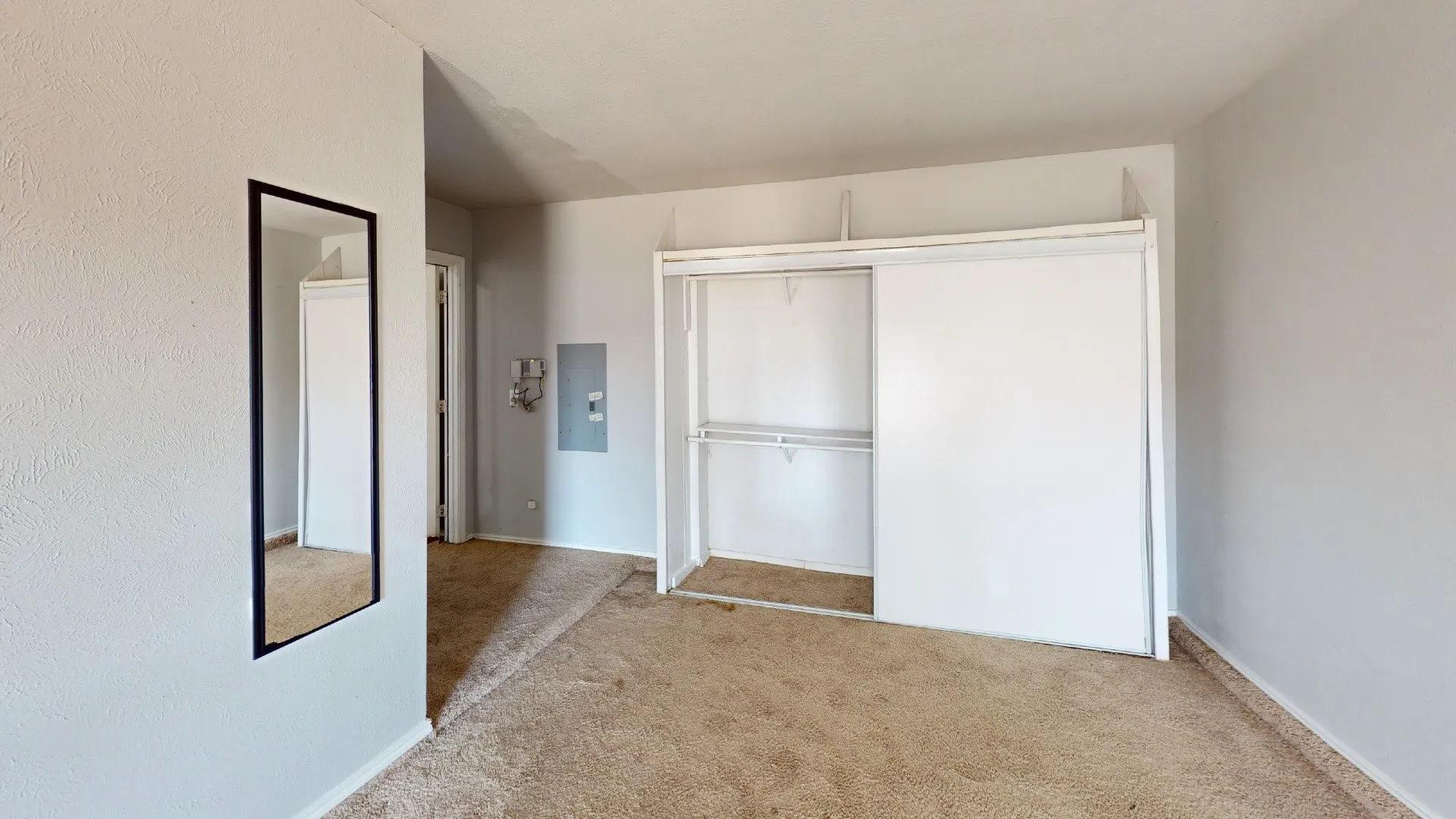 Wall-to-wall carpeting and sliding closet doors with built-in shelving