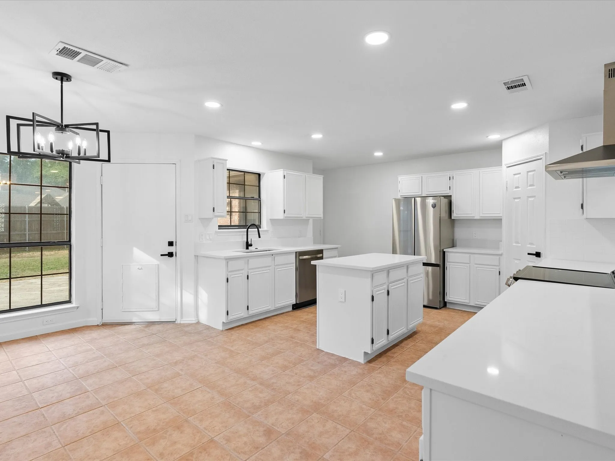 Kitchen featuring white cabinetry, a central island, stainless steel appliances, white countertops, and tile flooring