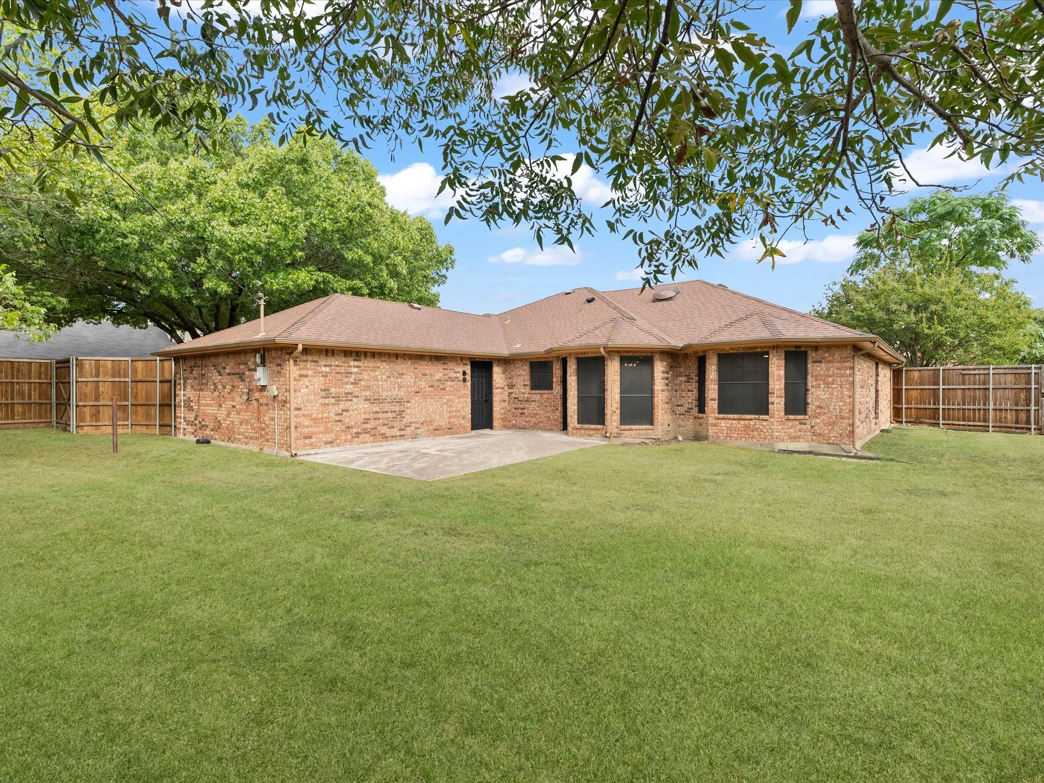 Expansive backyard featuring a manicured lawn, a large concrete patio, and a privacy fence