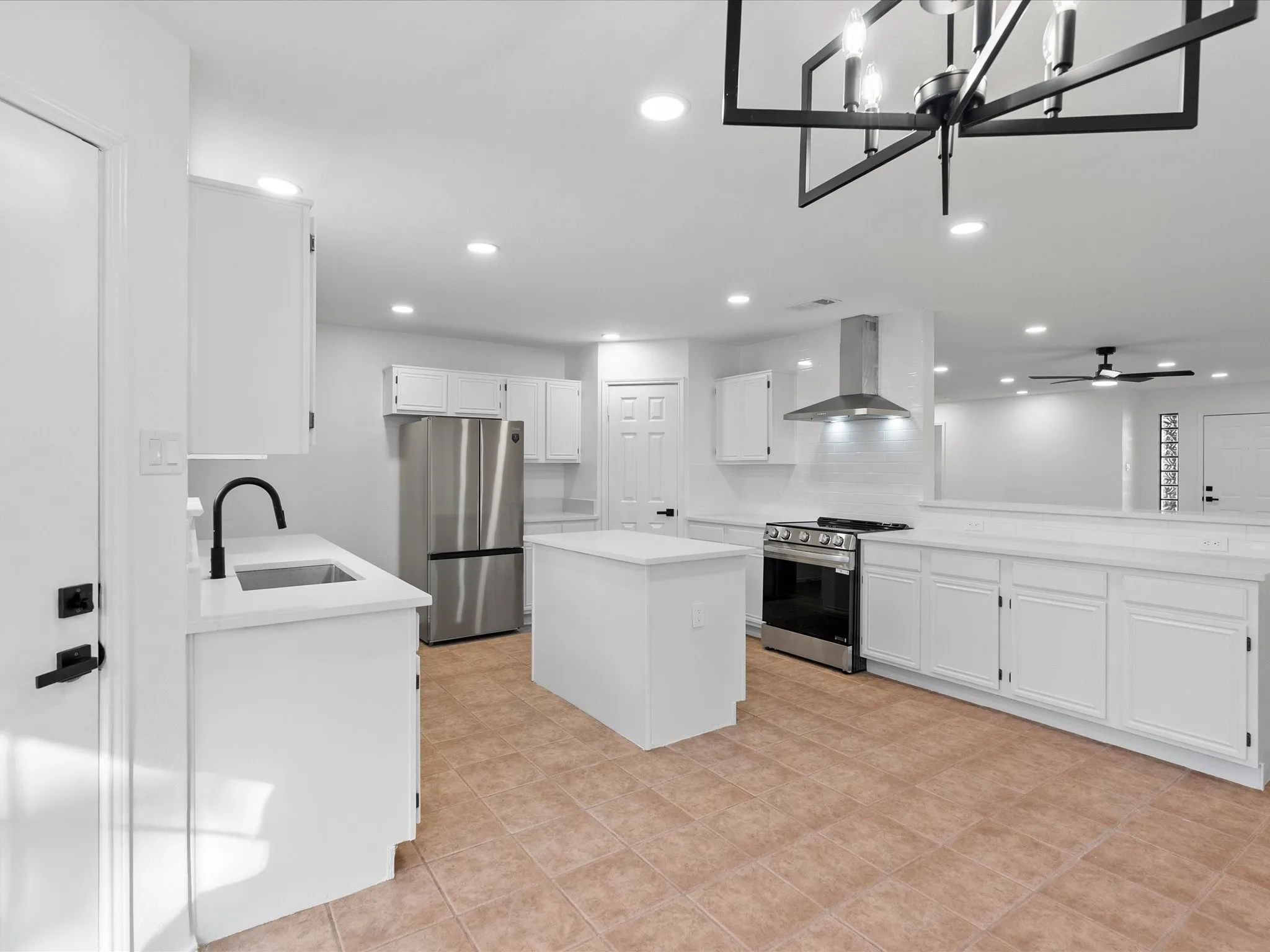 Updated kitchen featuring white shaker cabinetry, stainless steel appliances, a center island, and recessed lighting