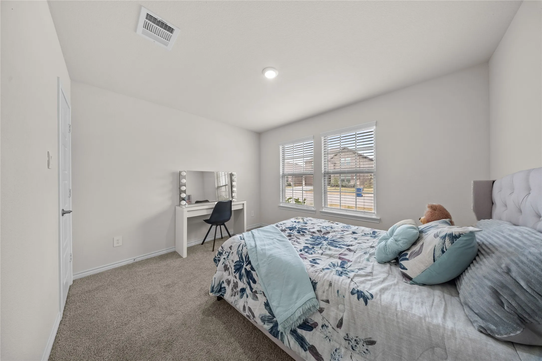 Neutral wall paint, light gray carpet, and two windows with blinds