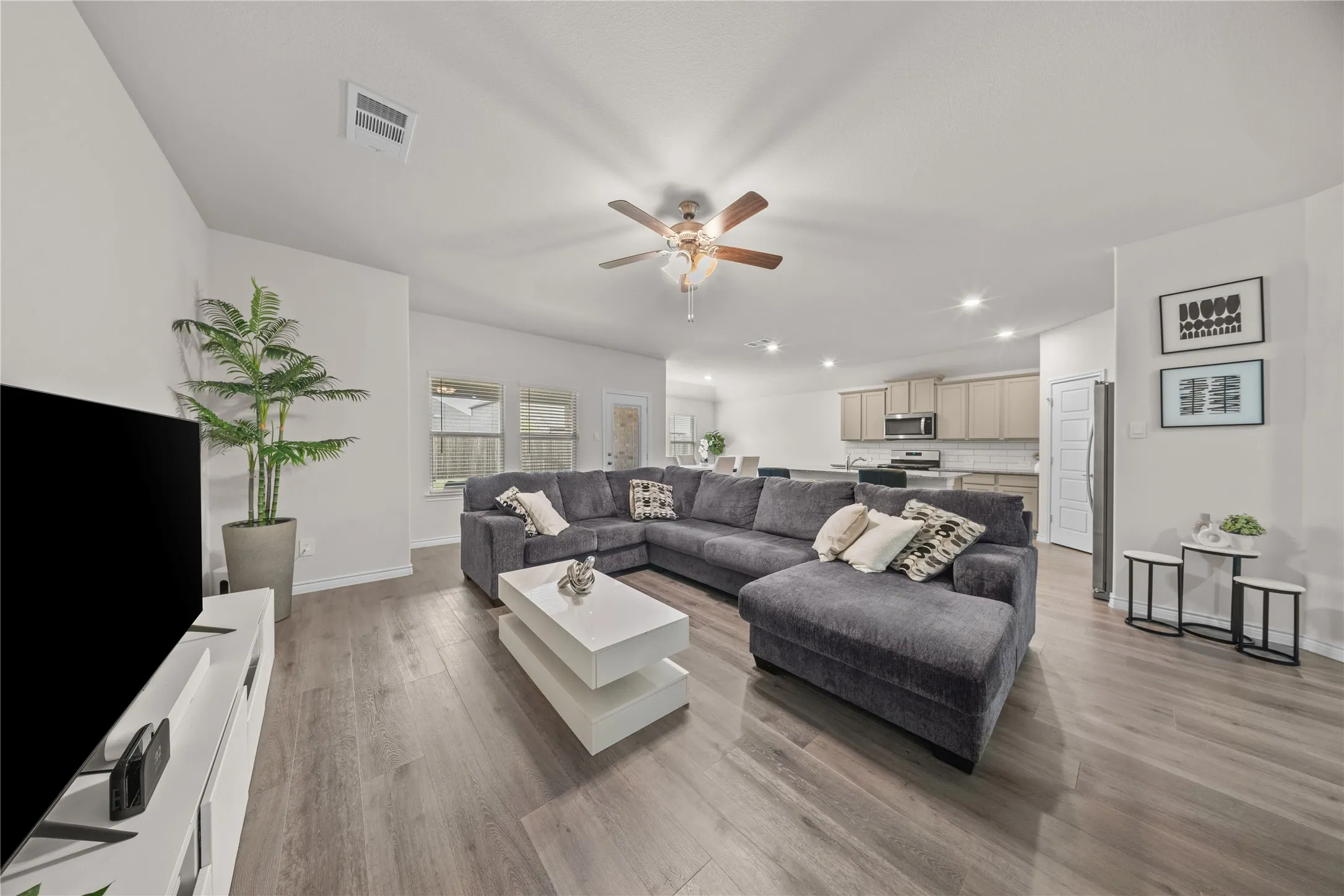 Open-concept living space with wood-finish flooring, recessed lighting, and a ceiling fan