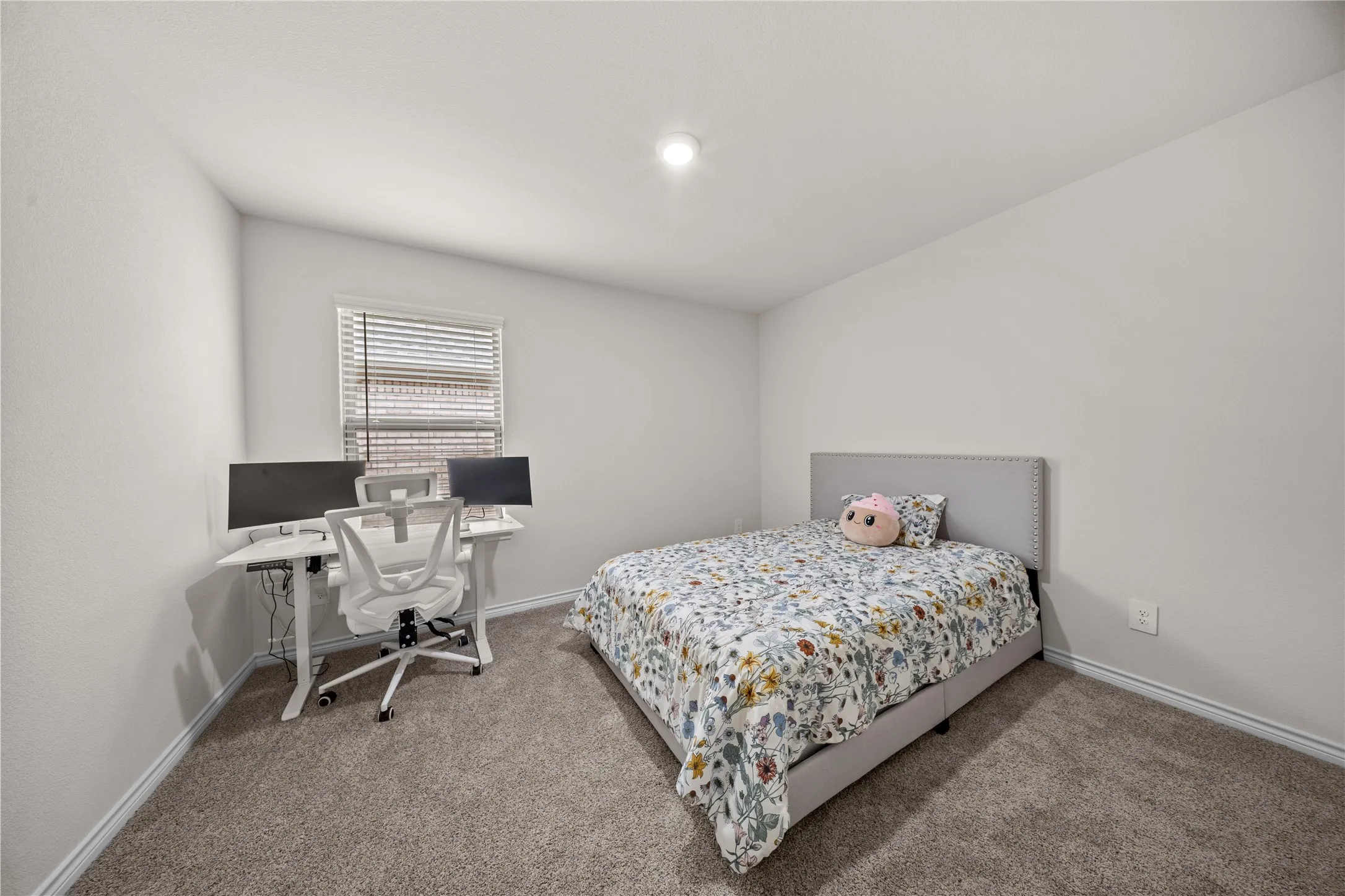 Neutral wall color, recessed ceiling lighting, window with blinds, carpet flooring, and a fabric upholstered headboard
