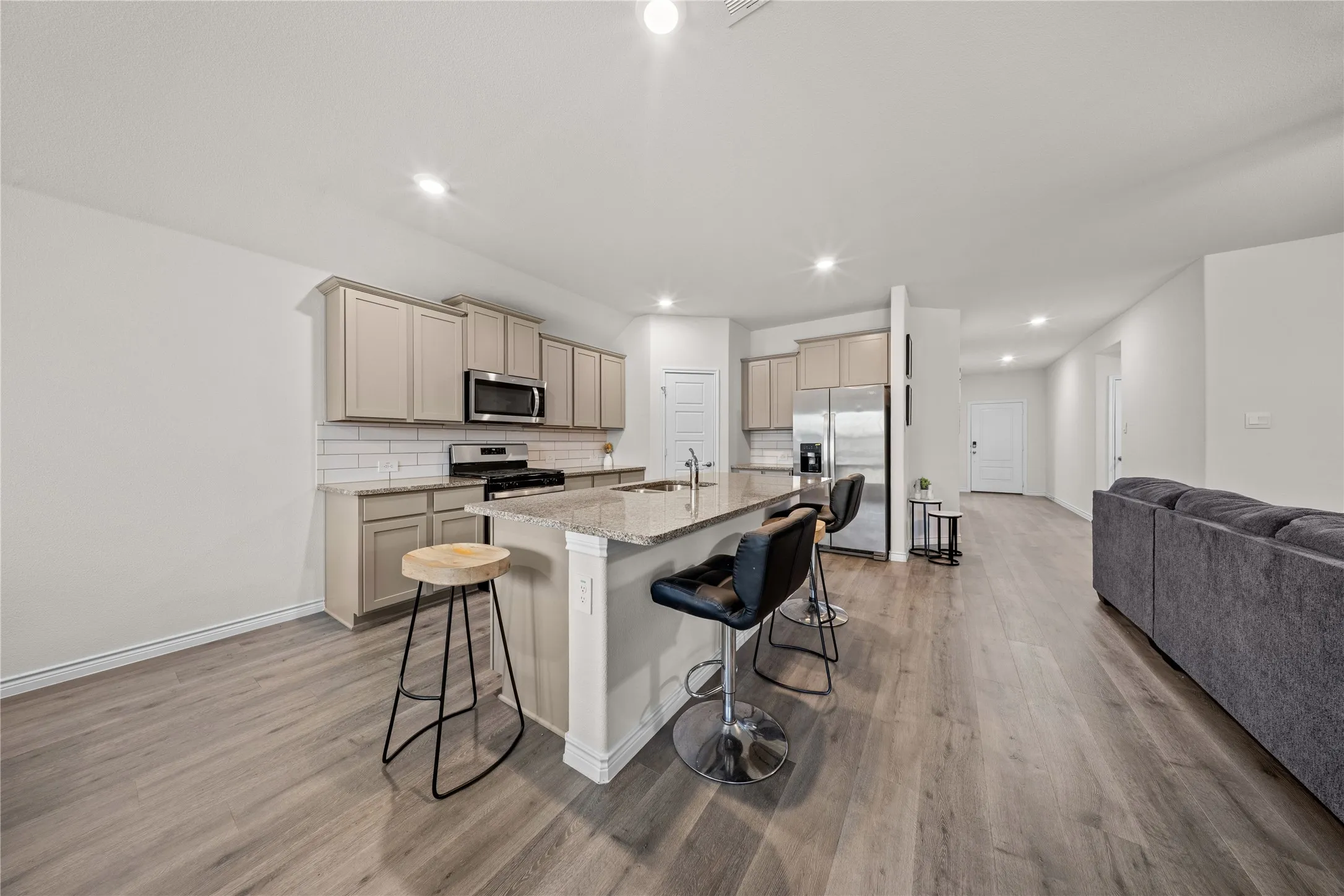 Kitchen island with granite countertop, stainless steel appliances, light wood-finish flooring, and recessed lighting