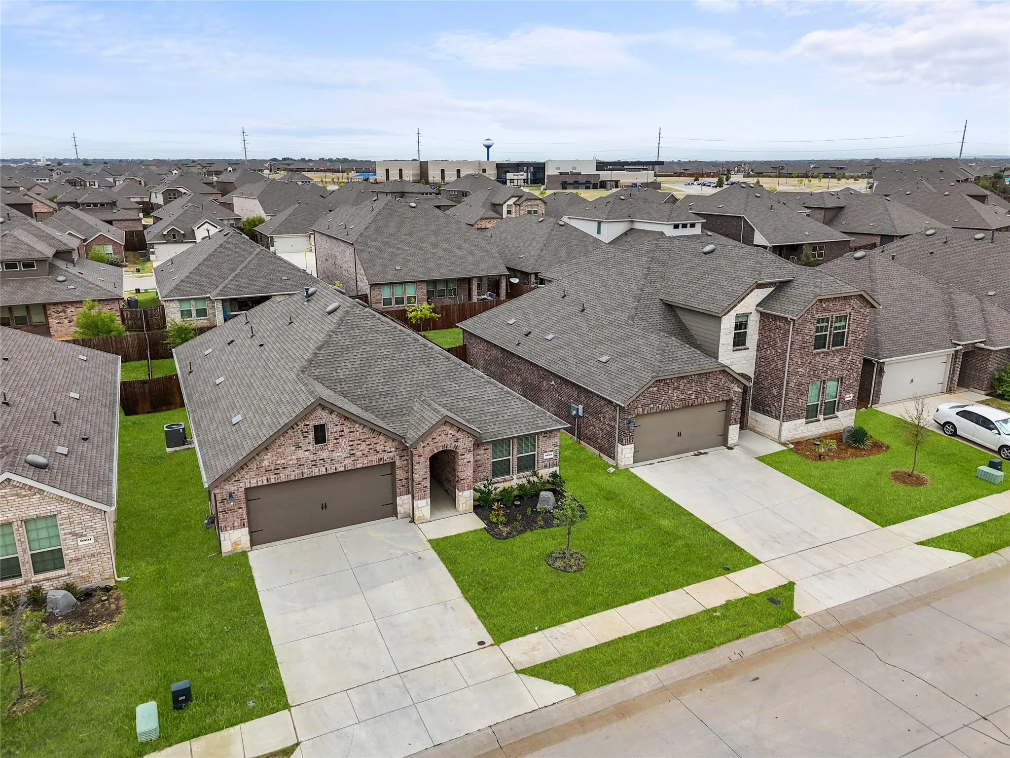 Brick facade, attached garage, concrete driveway, and a manicured lawn