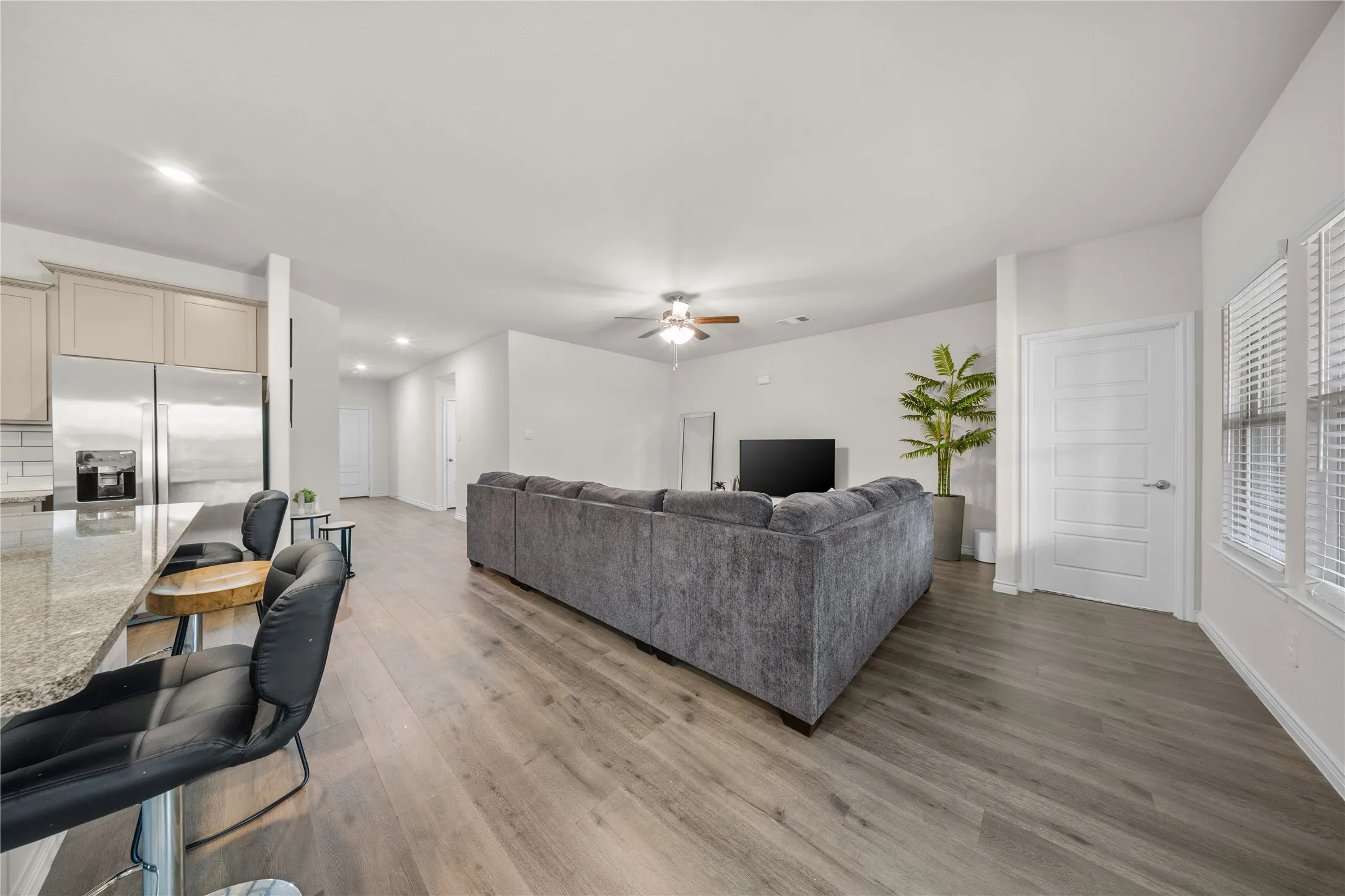 Open-concept living area with wood-finish flooring, a ceiling fan, and white paneled doors