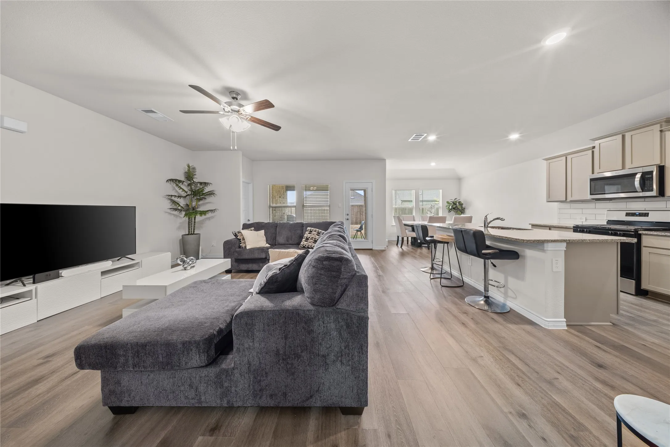 Open-concept living area featuring wood-finish flooring, recessed lighting, and a ceiling fan