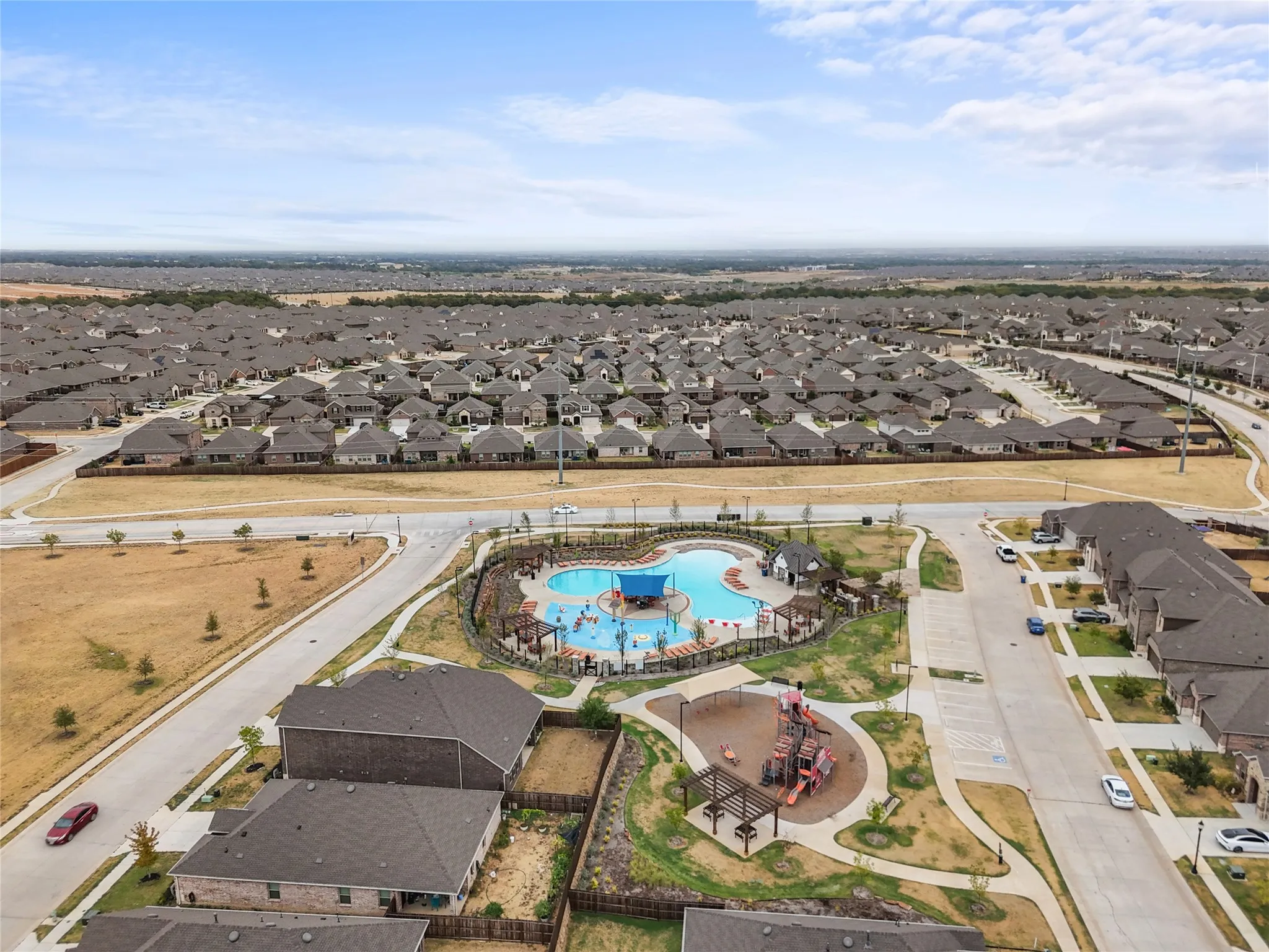 Community pool with water features, adjacent playground, and paved walking paths