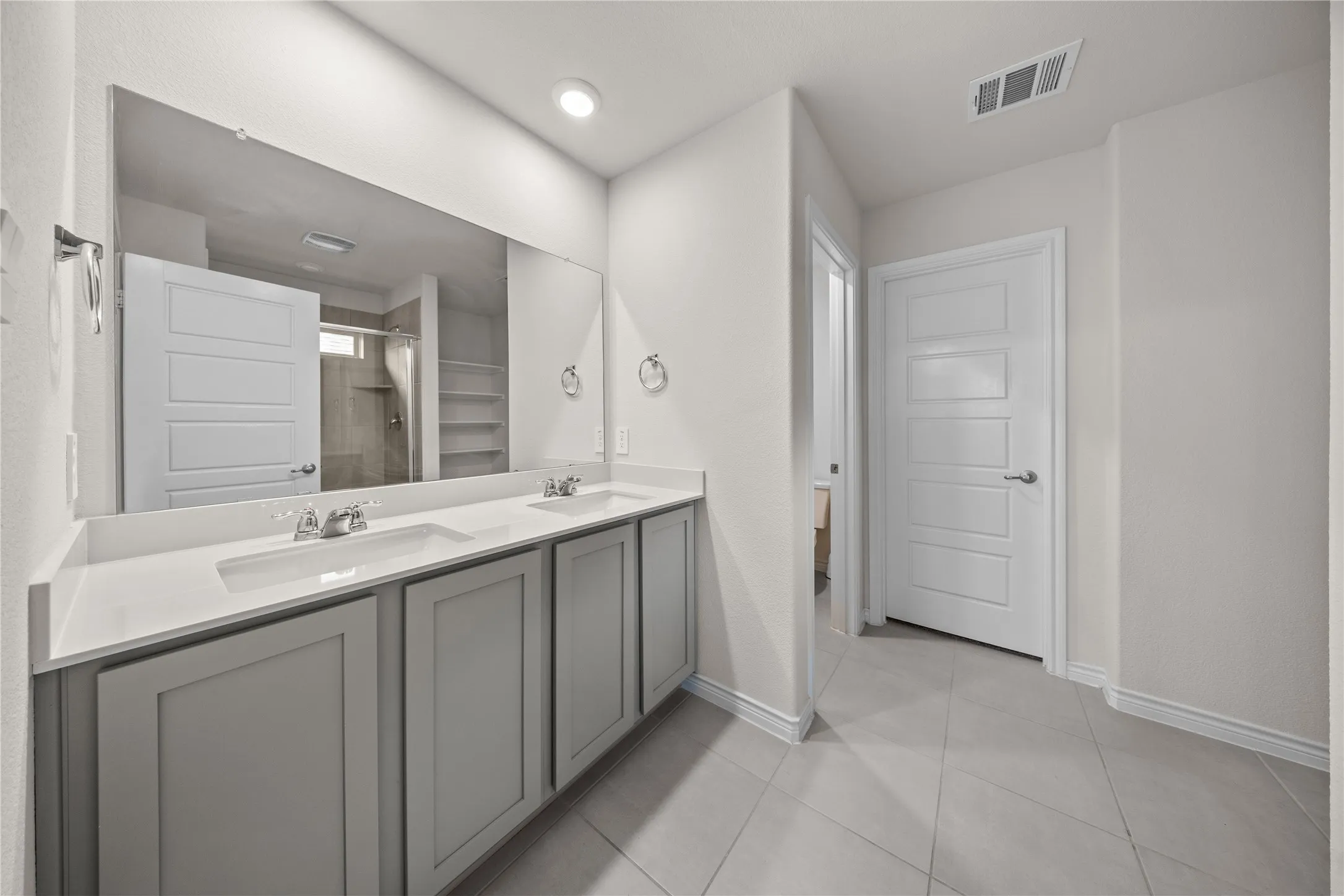 Dual vanity with light gray cabinetry, white countertops, and undermount sinks
