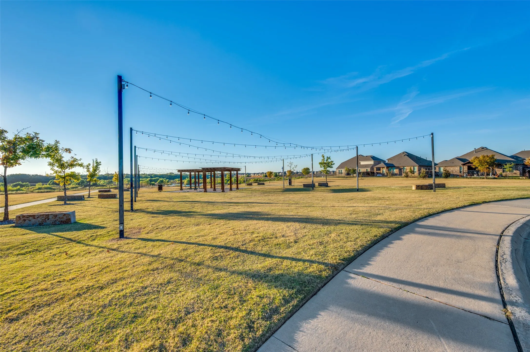 Expansive community green space featuring string lighting, a walking path, and a pergola