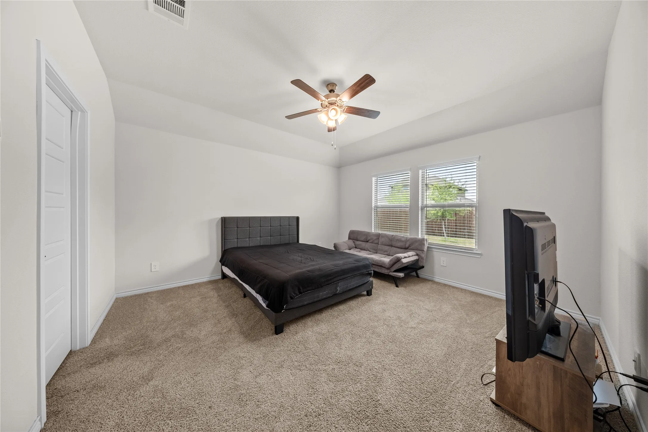 Carpeted room with a ceiling fan, two windows, and a white paneled door