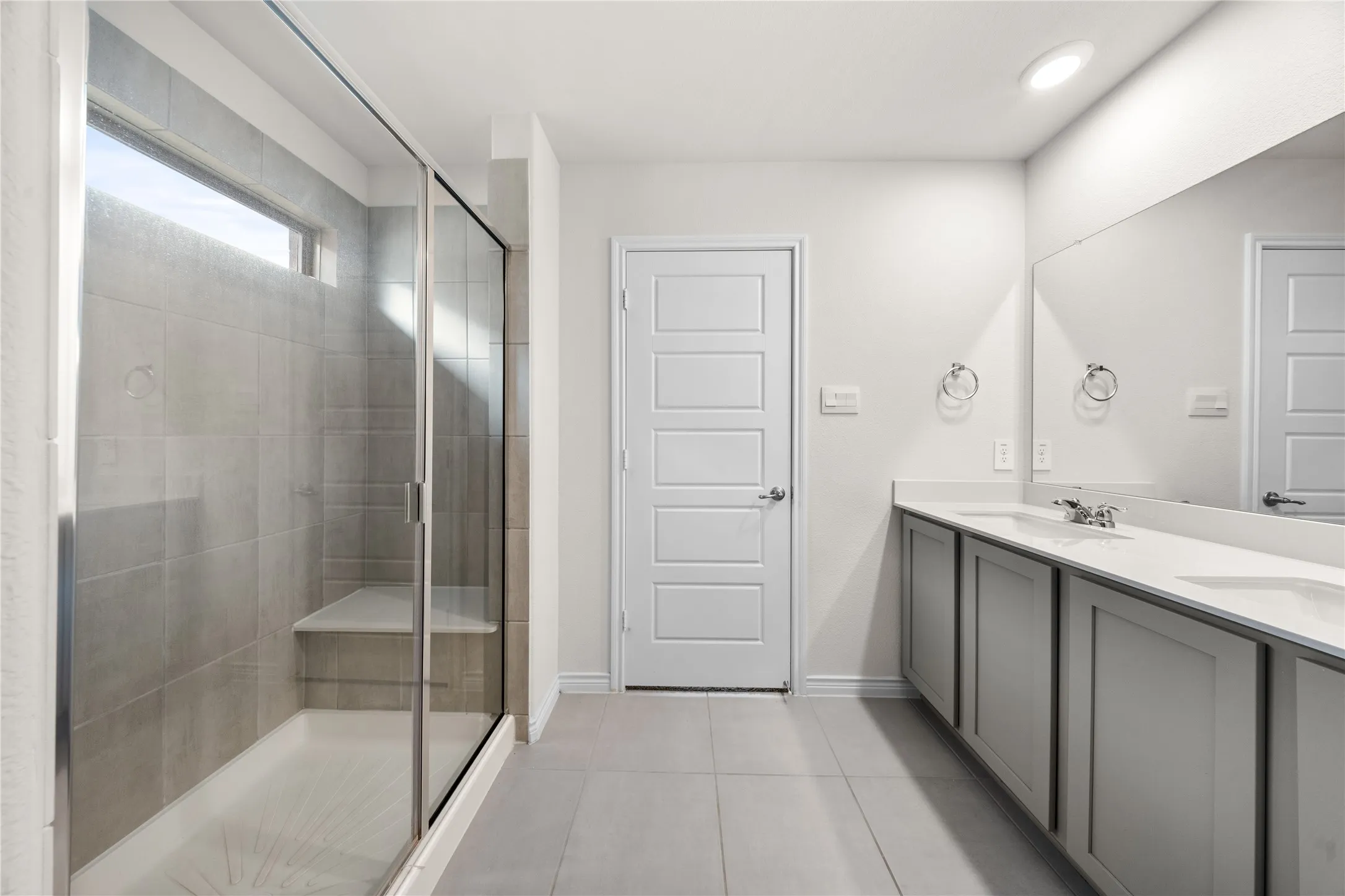 Dual sink vanity with light gray cabinetry and integrated countertop