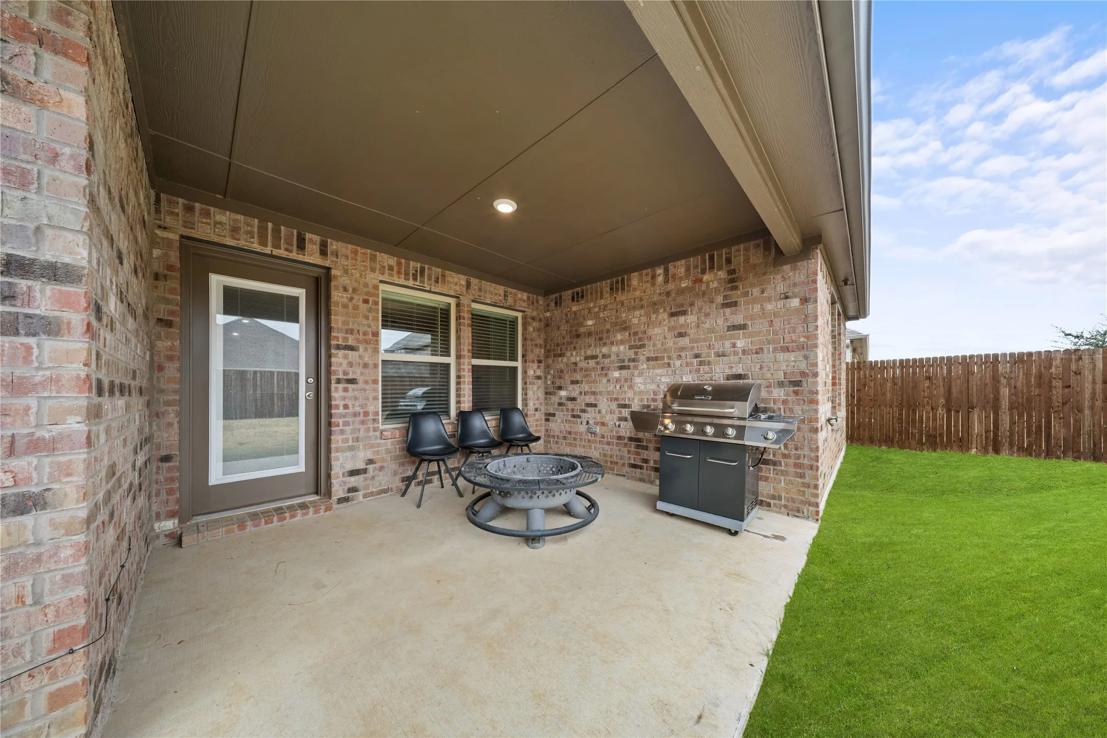 Covered patio with a concrete surface, brick exterior, and a fenced backyard