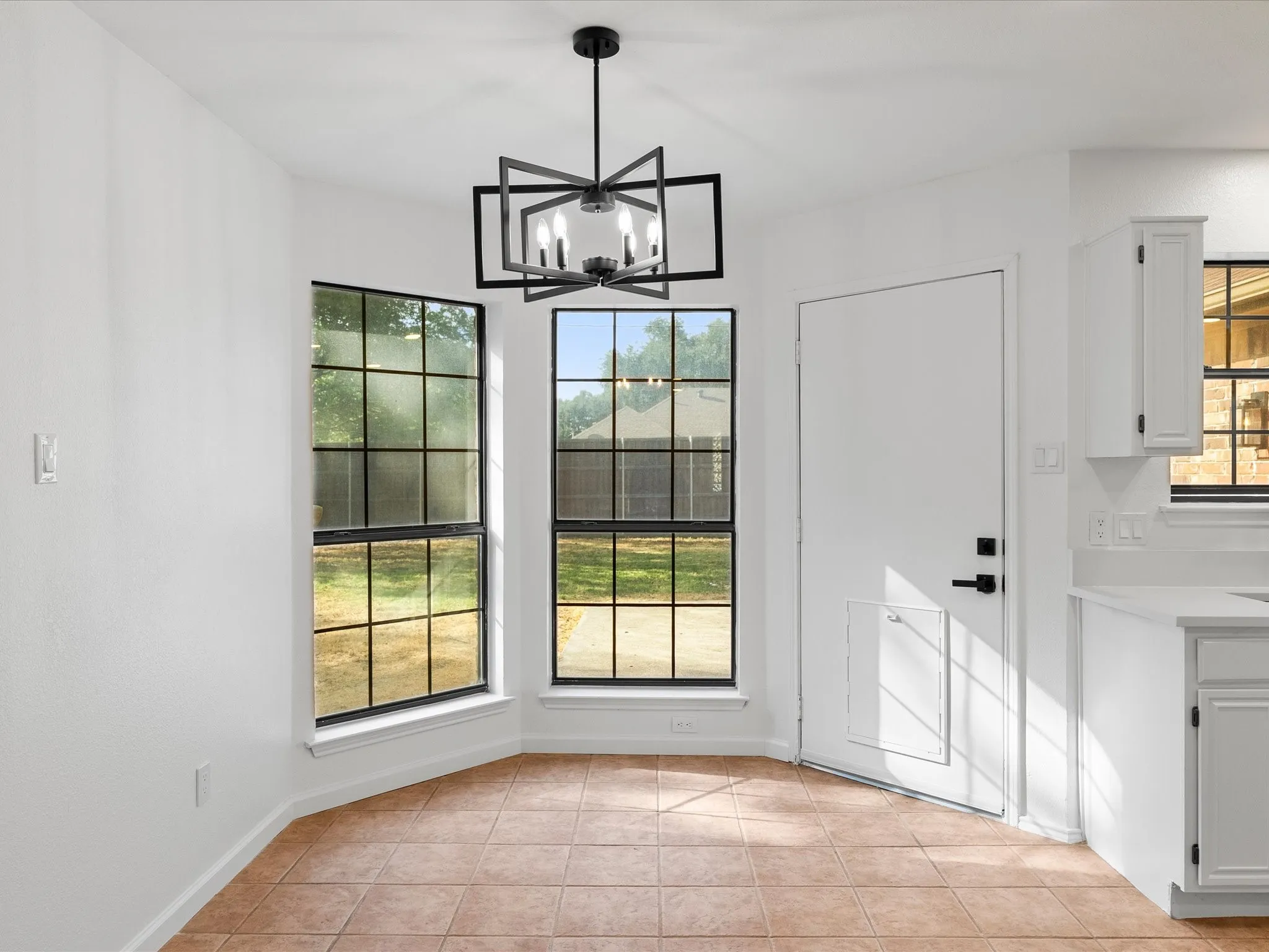 Recessed dining nook with ceramic tile flooring, a modern chandelier, and multiple windows