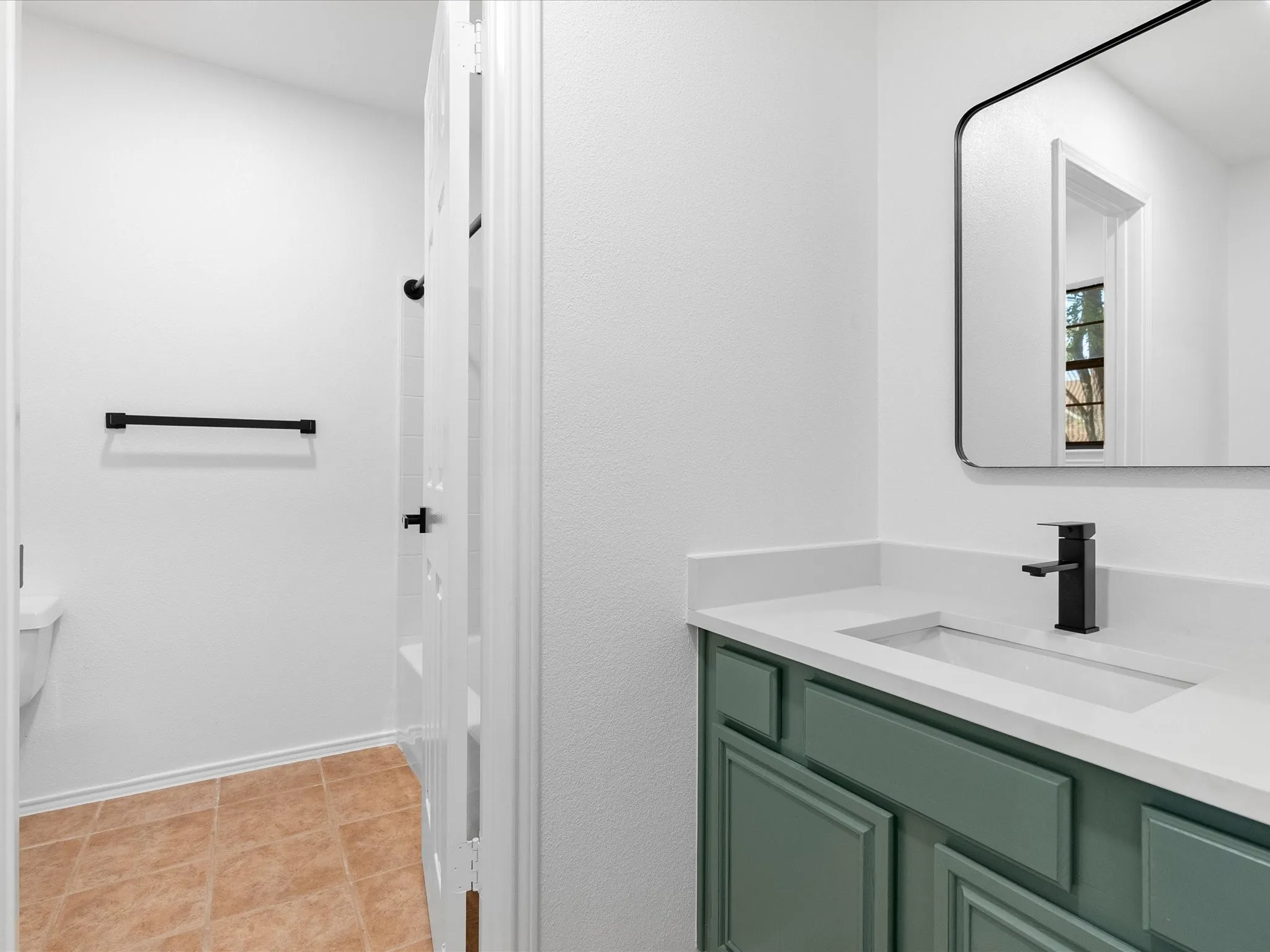 Vanity with a light green finish, white countertop, integrated sink, and matte black faucet
