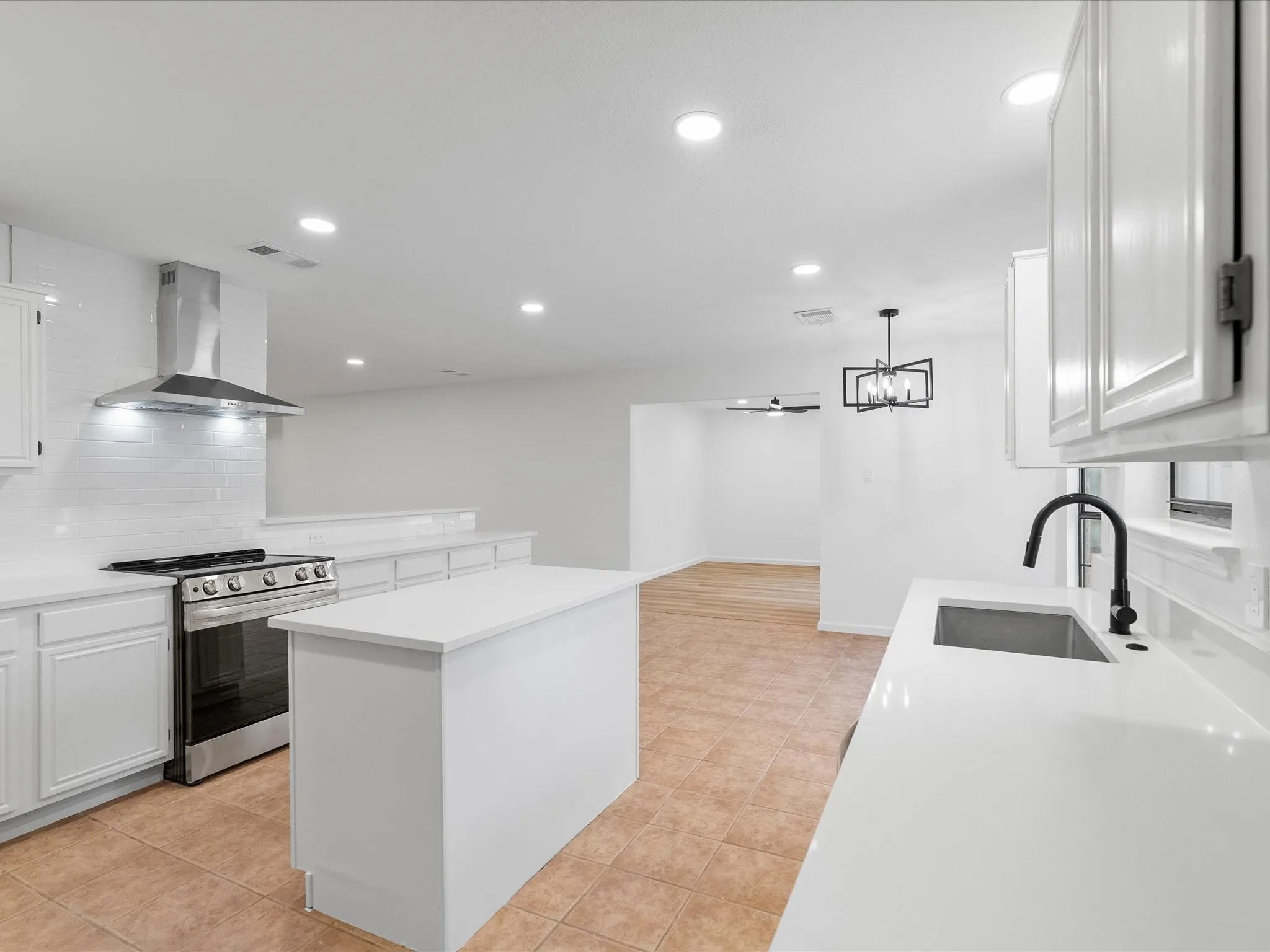 Kitchen featuring white shaker cabinetry, white subway tile backsplash, stainless steel range with ventilation hood, and white countertops