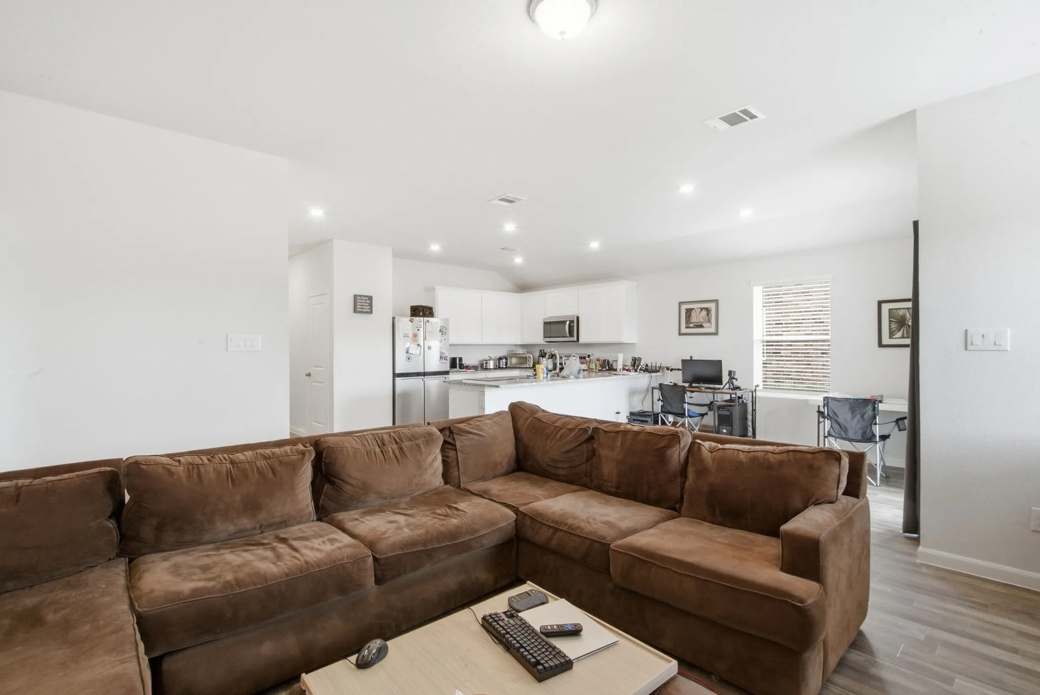 Open-concept living area with wood-finish flooring, recessed lighting, and white walls