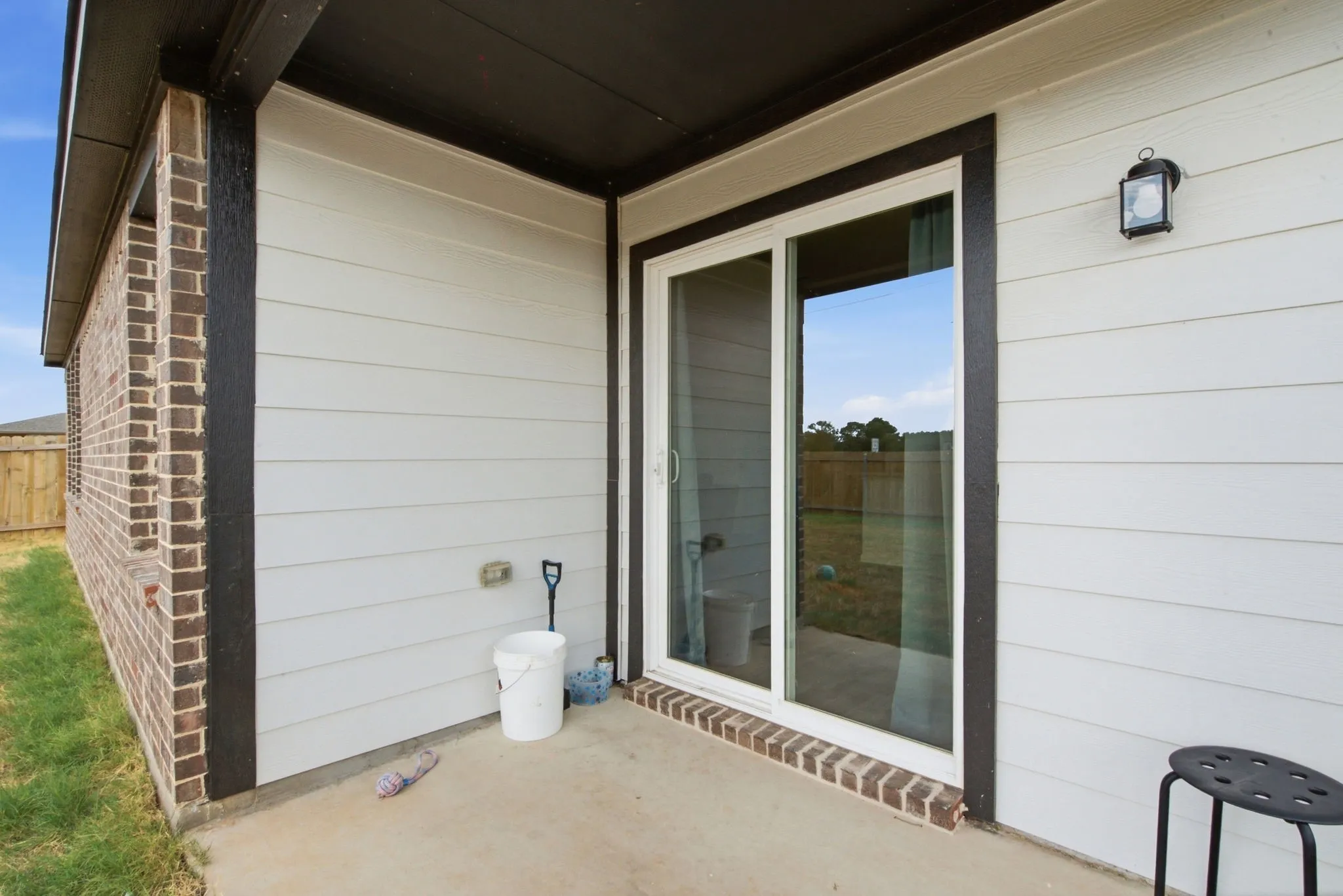Patio featuring a sliding glass door, brick detailing, and exterior lighting