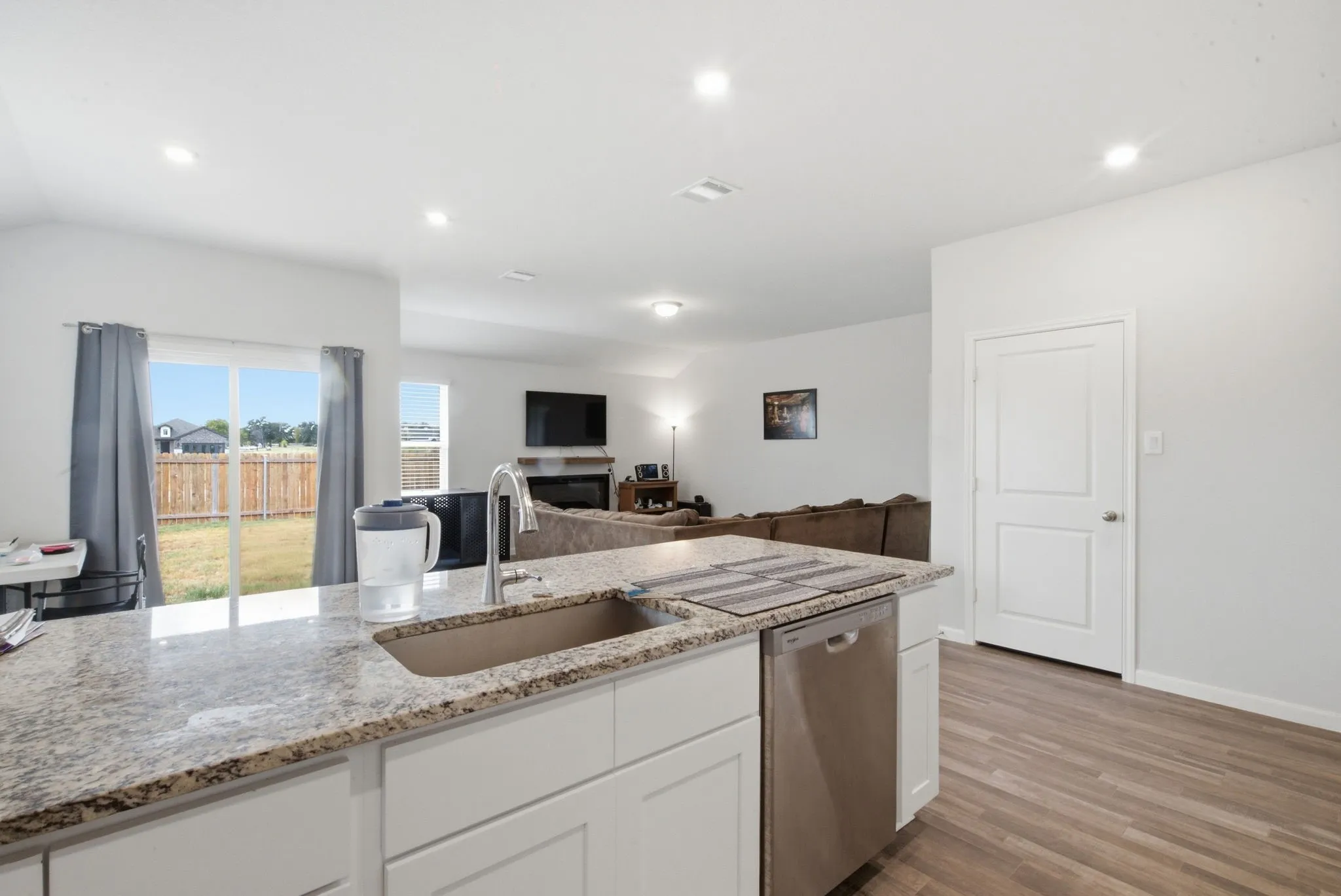 Kitchen island with a built-in sink, granite countertops, and white cabinetry