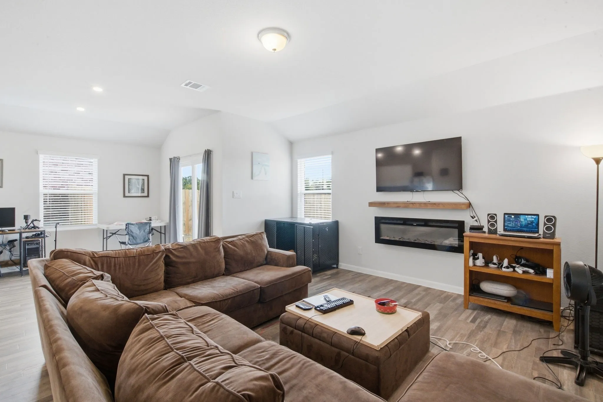 Spacious living area featuring wood-finish flooring, recessed lighting, and a modern fireplace with a floating mantel