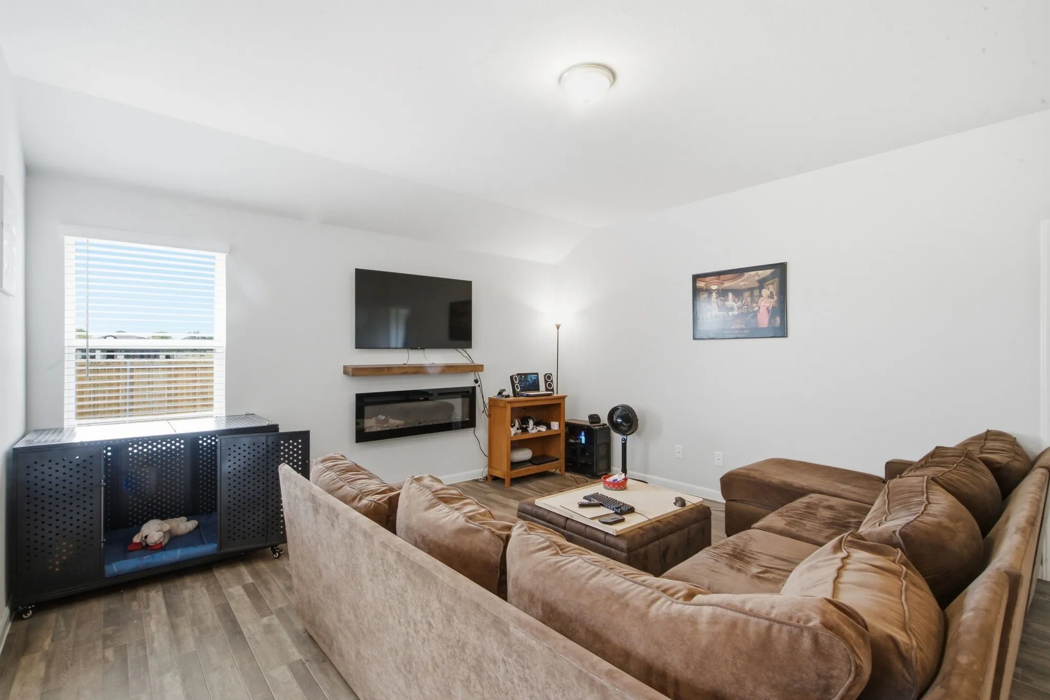 Wood-finish flooring throughout, featuring a wall-mounted electric fireplace with a wood mantel