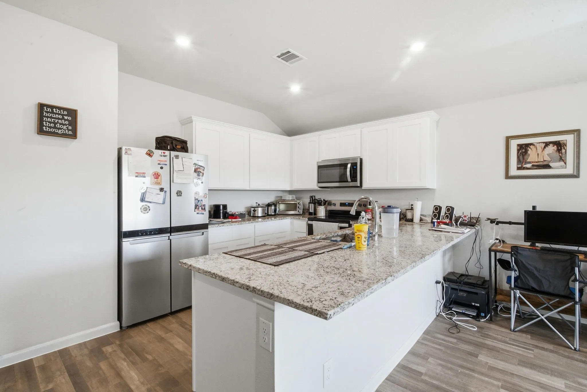 Kitchen featuring white cabinetry, stainless steel appliances, speckled stone countertops, and wood-finish flooring