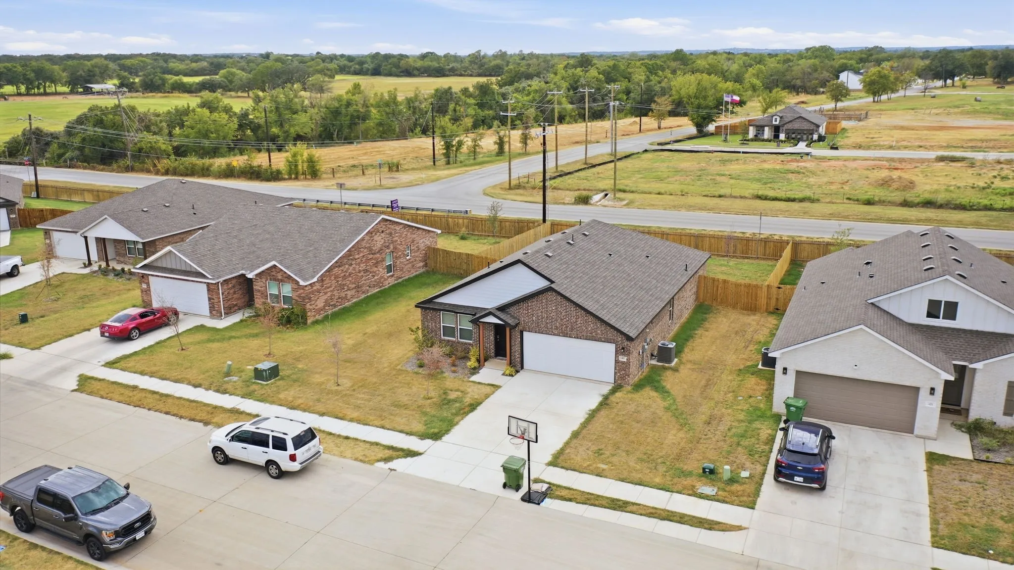 Brick and siding exterior, concrete driveway, attached garage, shingled roof, and a fenced backyard