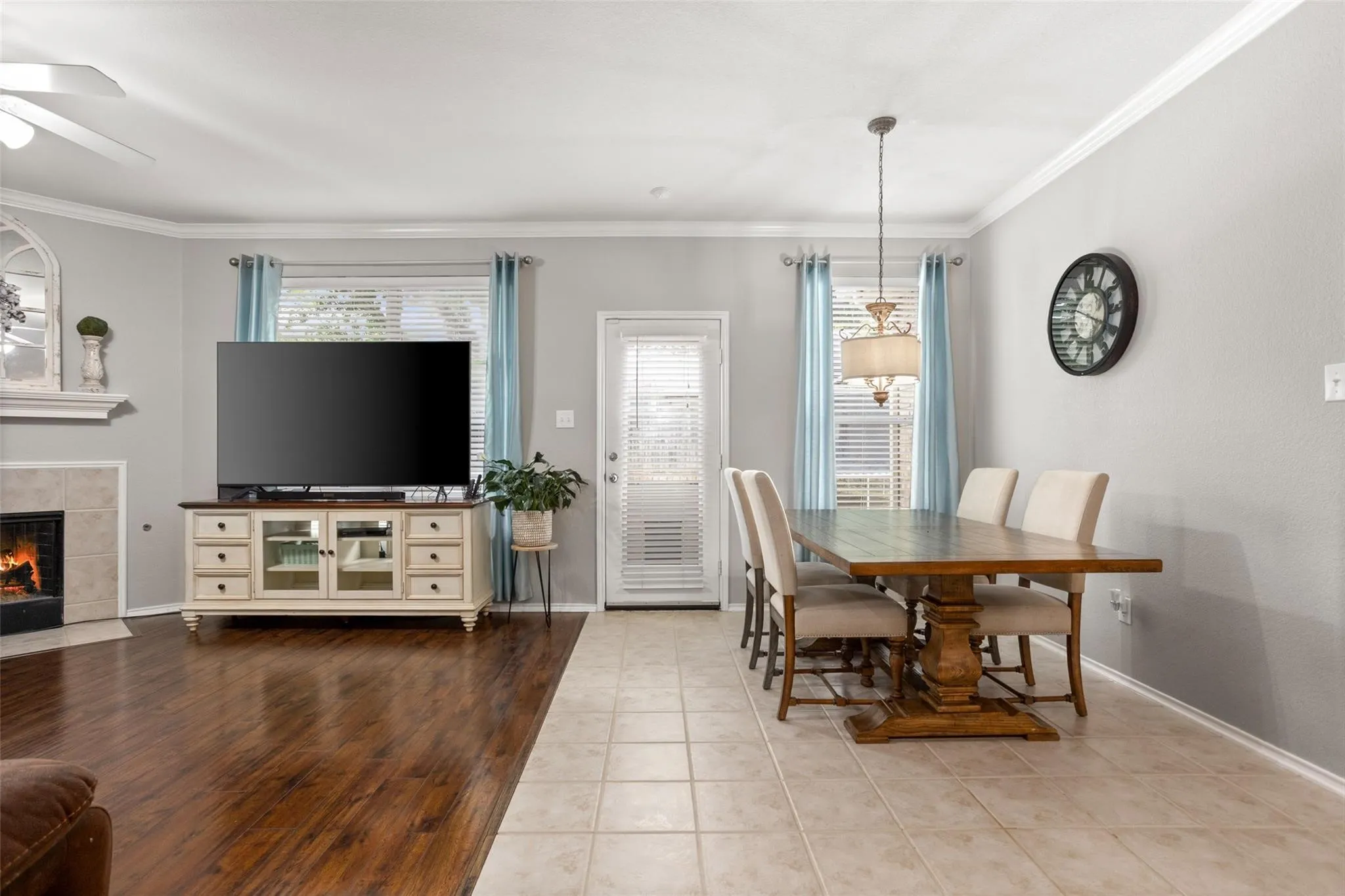Wood-finish flooring, tiled flooring, recessed fireplace with hearth, crown molding, and a ceiling fan with light fixture