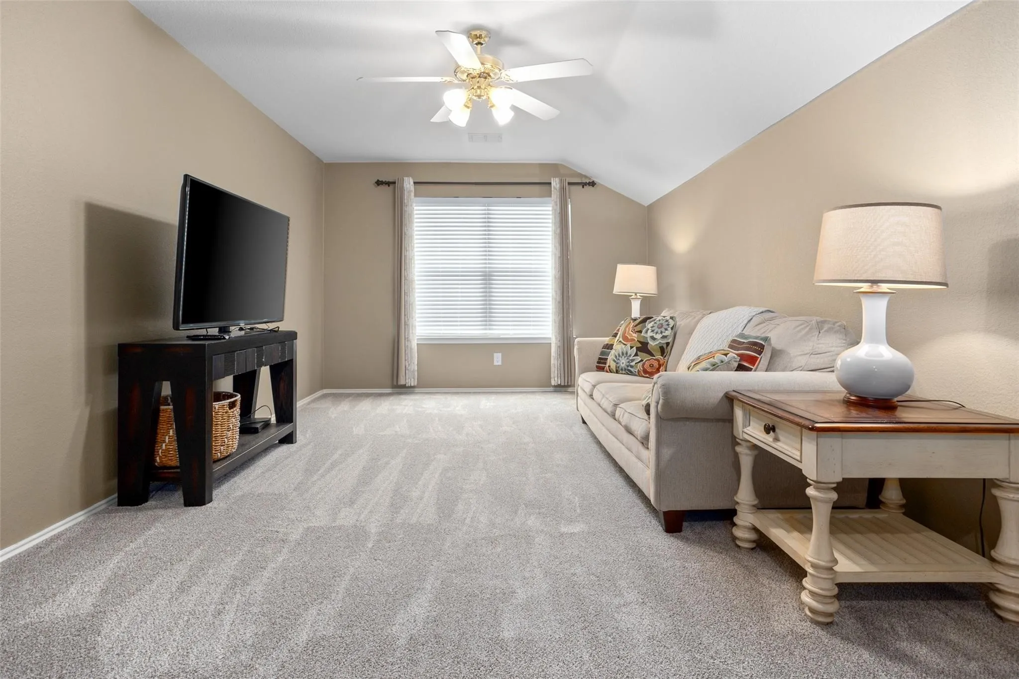 Recessed window with blinds, ceiling fan with integrated lighting, textured carpet flooring, and a neutral wall color
