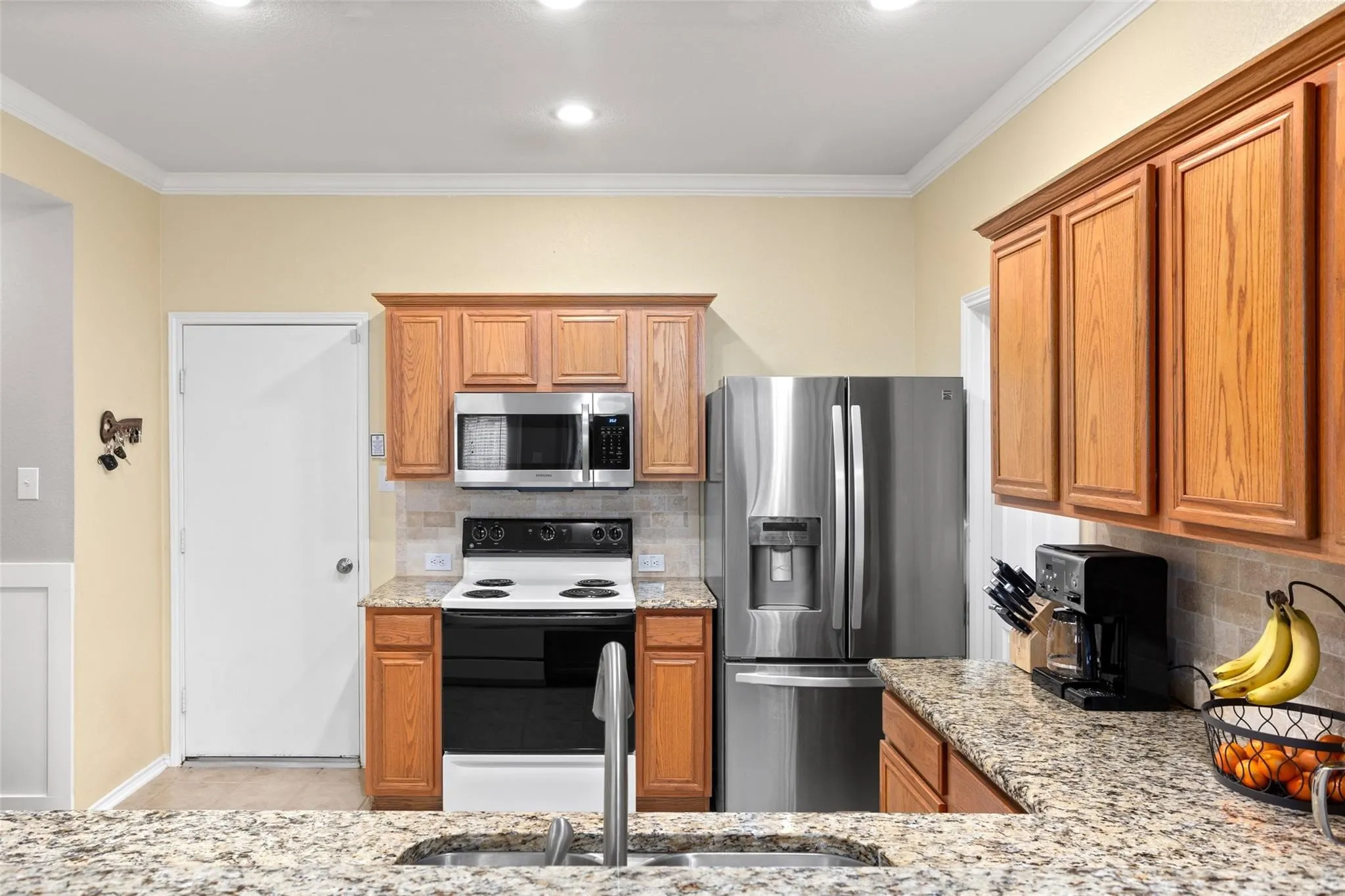 Kitchen featuring wood cabinetry, stainless steel appliances, speckled countertops, and a tiled backsplash