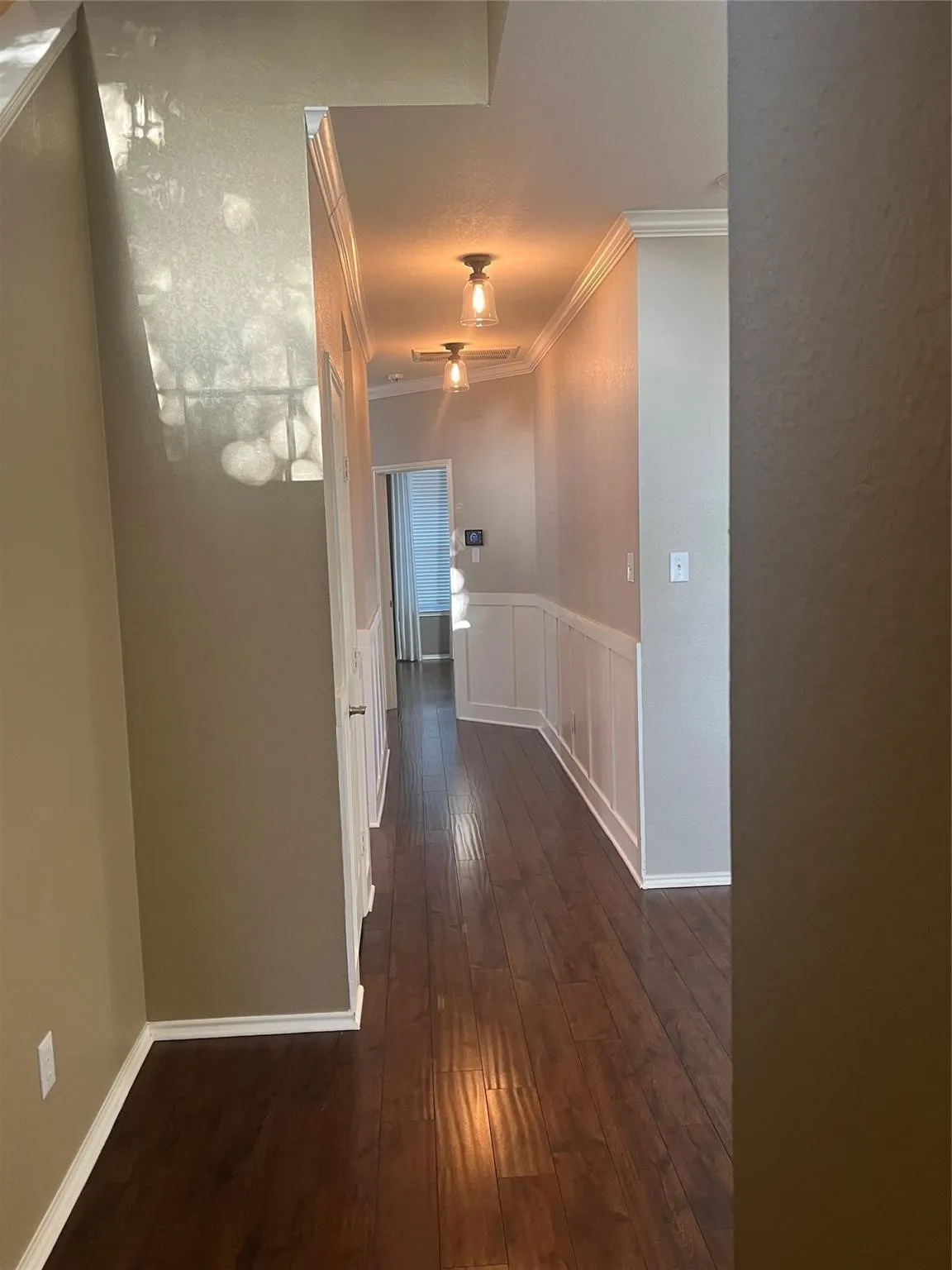 Wood-finish flooring with crown molding, wainscoting, and recessed lighting