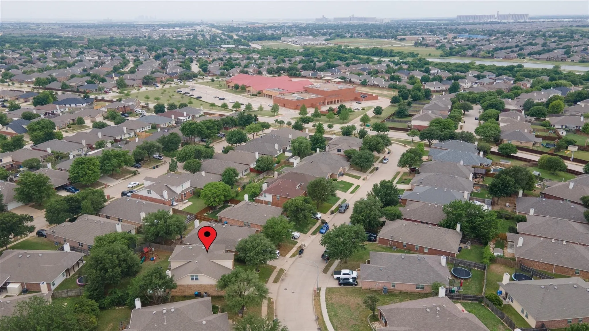 Aerial perspective highlighting a residential neighborhood with a variety of single-story homes, mature landscaping, and a nearby community building
